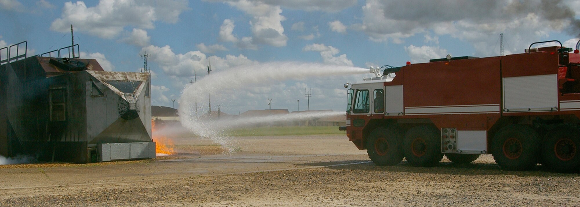 The first fire truck at the fire pit shoots water onto a mock aircraft fire during the exercise June 25. RAF Mildenhall conducted a base-wide Phase II exercise June 24 to 26 to better prepare Airmen for deployments and wartime environments and to train for the upcoming operational readiness inspection in 2009. (U.S. Air Force photo by Karen Abeyasekere)
