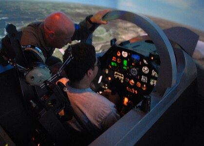 Airman 1st Class Kevin Krogh, with the 27th Aircraft Maintenance Unit at Langley Air Force Base, Va., mans the controls of a T-6A Texan II flight simulator during a tour of Randolph Air Force Base, Texas, June 27. Thirteen wounded warriors who are currently receiving care at the Center for the Intrepid at Brooke Army Medical Center in San Antonio, joined base leaders for a VIP tour of Randolph AFB to learn about the 12th Flying Training Wing mission. (U.S. Air Force photo by Rich McFadden)
