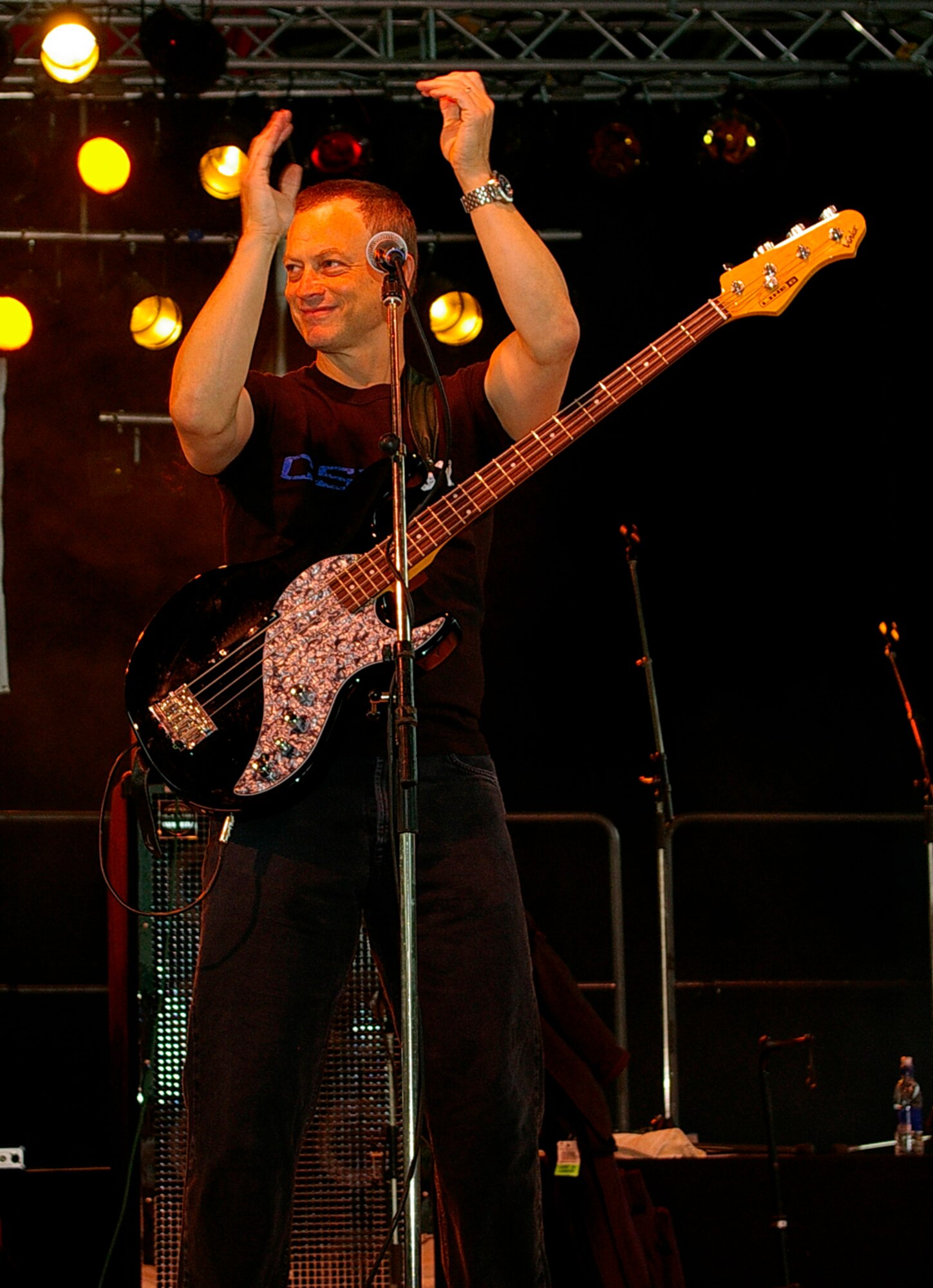 Actor Gary Sinise, bass guitarist and founder of the Lt. Dan Band, encourages the crowd to clap along to the music as he and the rest of the band entertain Airmen and their family members at RAF Mildenhall June 29. The band was here as part of a United Services Organization tour, playing to servicemembers around the world to show their support for them. Approximately 650 people watched the concert as the Lt. Dan Band interacted with the crowd and kept everyone entertained for the two-hour show. (U.S. Air Force photo by Karen Abeyasekere)