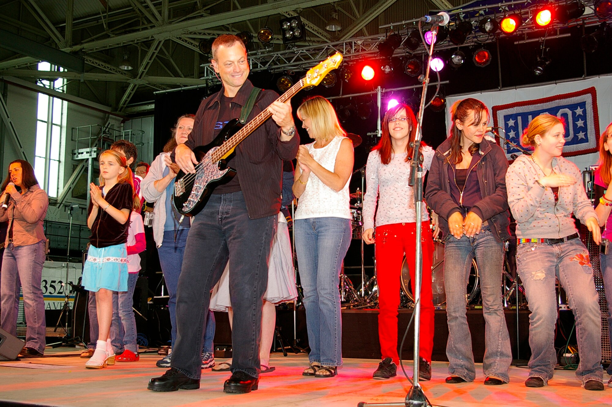 Actor Gary Sinise plays bass guitar alongside some of the female members of the audience during a Lt. Dan Band rendition of "Lady Marmalade" June 29 at RAF Mildenhall. The band was here as part of a United Services Organization tour, playing to servicemembers around the world to show their support. Approximately 650 people watched the concert as the Lt. Dan Band interacted with the crowd and kept everyone entertained for the two-hour show. (U.S. Air Force photo by Karen Abeyasekere)