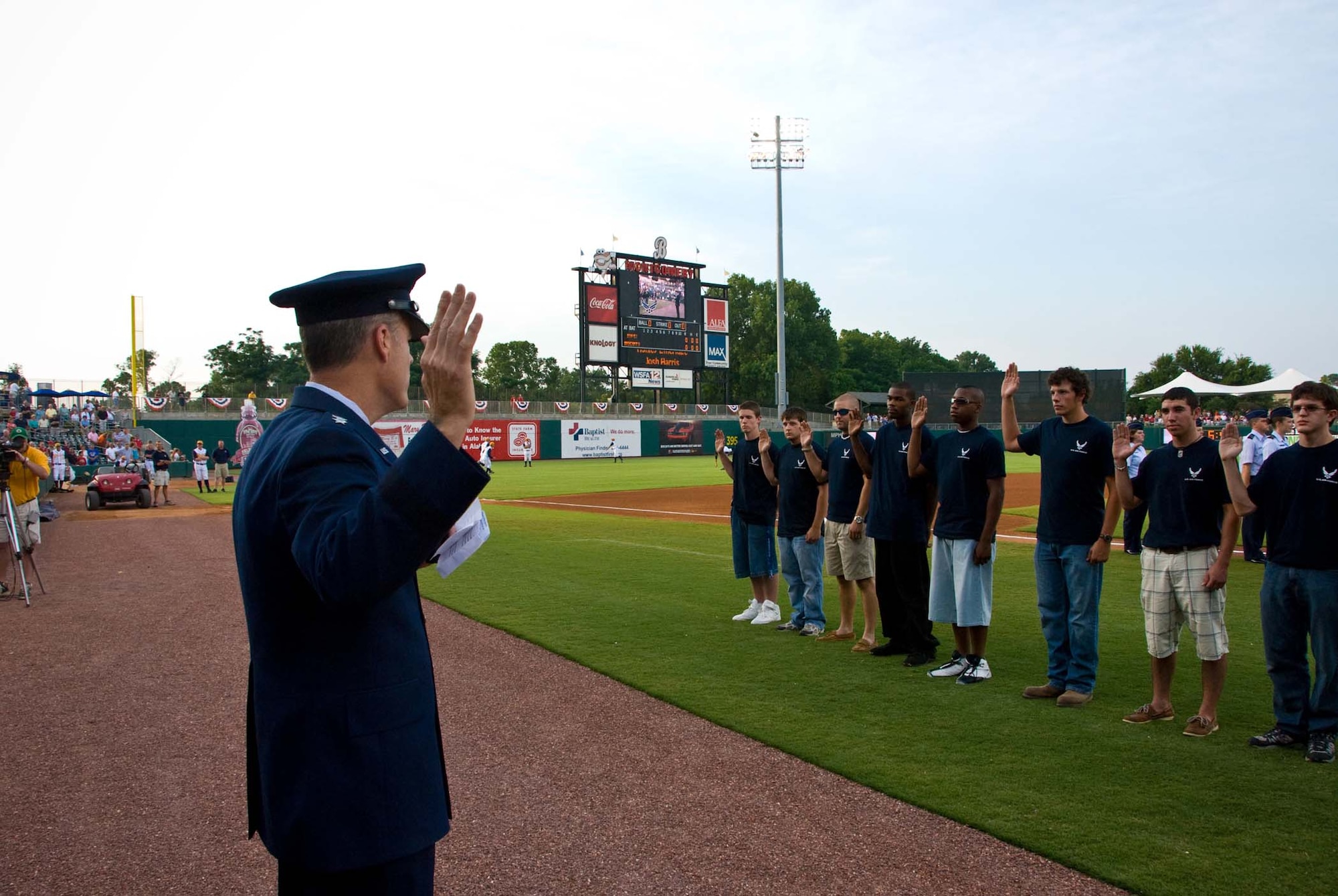 Lt. Gen. Allen G. Peck, Air University commander, administers the oath of enlistment to 21 future Airmen June 28, during the Montgomery Biscuits Military Appreciation Night. (U.S. Air Force photo)