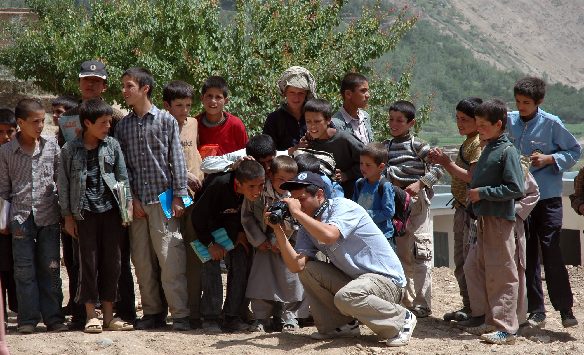 PANJSHIR PROVINCE, Afghanistan -- Azamat Kasybekov, a reporter with the Vechernyi Bishkek newspaper which is the only daily newspaper in the Kyrgyz Republic uses his digital camera to show students a photo he just took of them in Khenj on June 24.  Respected journalists from four major news media outlets in Kyrgyzstan visited the Panjshir Provincial Reconstruction Team to see how Manas Air Base, in Bishkek, Kyrgyz Republic fits into the bigger picture of Operation Enduring Freedom and International Security and Assistance Force efforts. (U.S. Air Force photo by Capt. Jillian Torango)