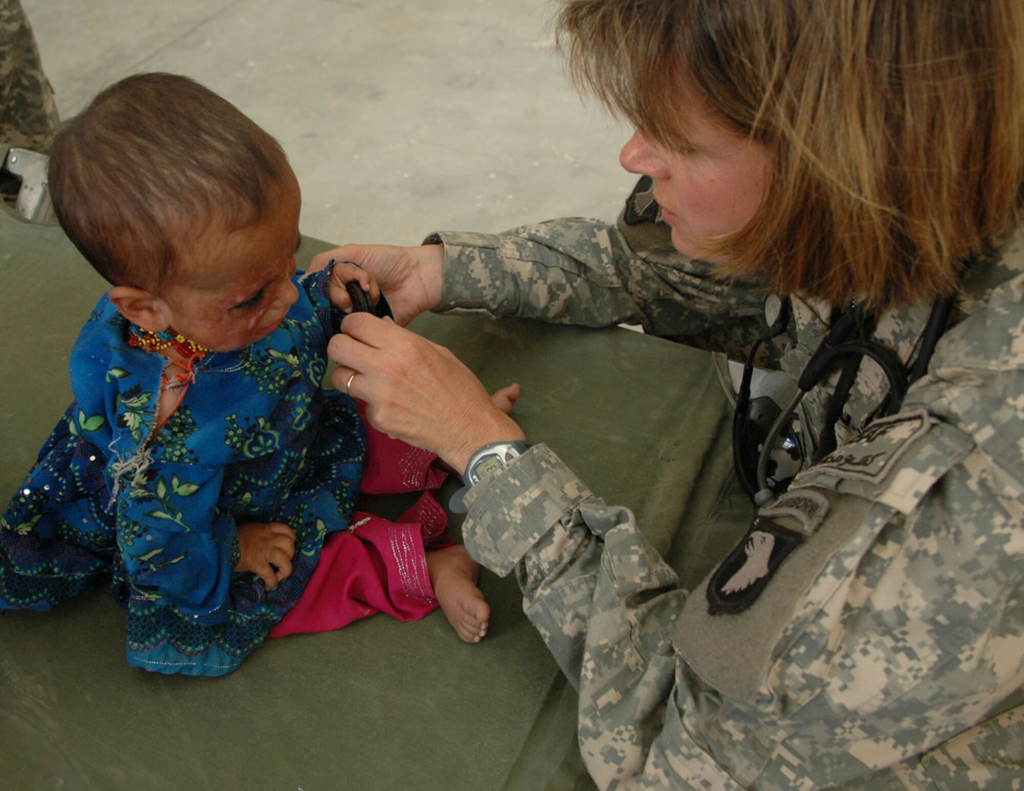 PARWAN PROVINCE, Afghanistan -- A young Afghan child receives a medical check tfor the burn scars on her face by Cmdr. Beth Myhre, the officer in charge of the cooperative medical assistance team, as part of a village medical outreach in Nilay Village in the Kohe Sofe District, here June 26. VMOs are missions that cooperate with the local doctors of villages to help bring in local nationals to get treated for ailments that might otherwise go untreated, and to help learn from each other on how to deal with different types of medical issues. (U.S. Army photo by Pvt. Tamara Gabbard)