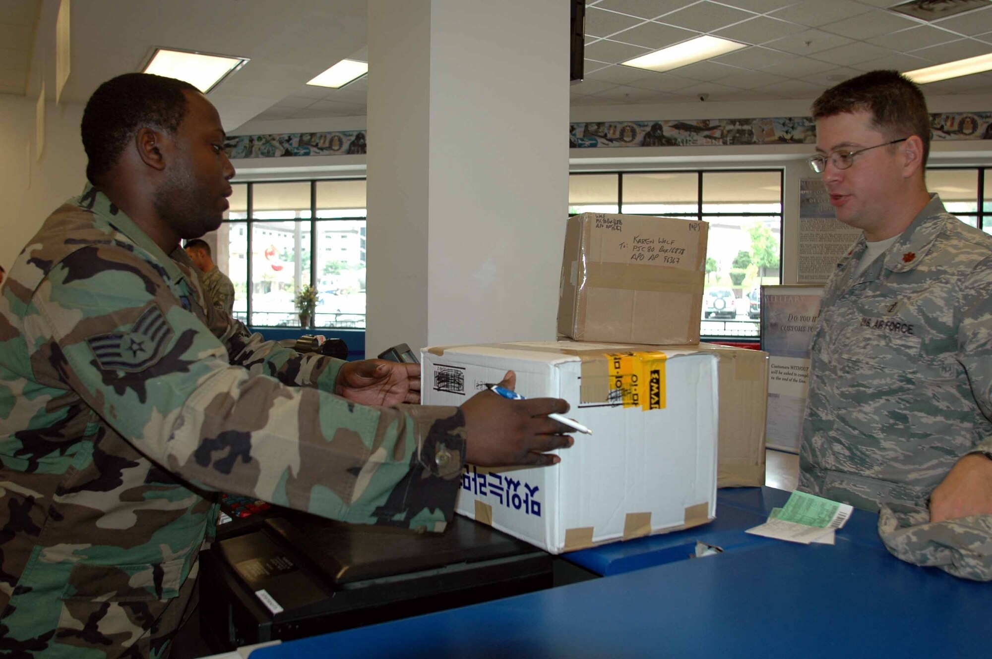 OSAN AIR BASE, Republic of Korea -- Staff Sgt. Aaron Green, postal clerk, weighs Maj. Stephen Wolf’s packages. The post office serves a population of more than 11,000 active-duty, DoD civilians, contractors and retirees. The 32-member team is responsible for providing Team Osan members with all the luxuries of a regular U.S.post office. (U.S. Air Force photo/Staff Sgt. Candy Knight)