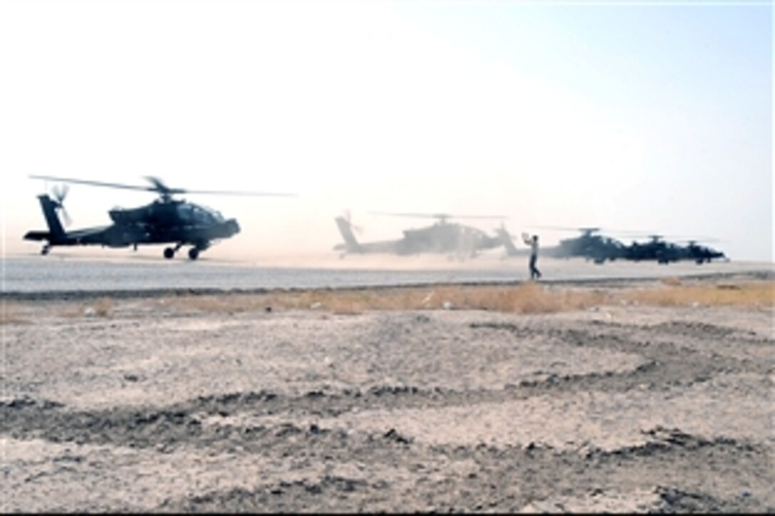 U.S. Air Force Senior Airman Brian Pittman signals an Army AH-64 Apache attack helicopter to park alongside several others at Ali Base, Iraq, June 30, 2008. 