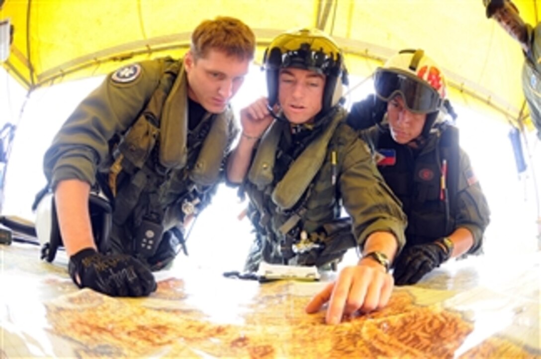 Briefing their next mission to a remote location Lt. Brandon Sheets, Petty Officer 2nd Class Travis Story (left) and Petty Officer 2nd Class Keith Holt (right) quickly gather all the pertinent information before flying out of Iloilo Airport in the Philippines on June 30, 2008.  Helicopters from Anti-Submarine Squadron 4 have been delivering food and water to remote locations on Panay Island that were hardest hit by Typhoon Fengshen.  At the request of the government of the Republic of the Philippines, the USS Ronald Reagan is off the coast of Panay Island providing humanitarian assistance and disaster relief.  The Ronald Reagan is operating in the 7th Fleet area of responsibility to support maritime security operations.  