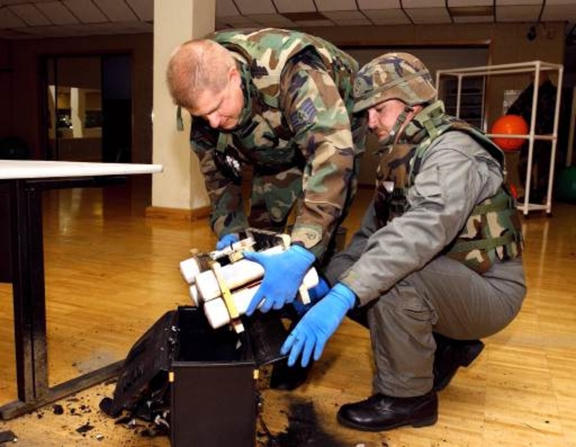 During an IED joint training exercise at Travis AFB, Master Sgt. Philip Hartzell (right) helps a trainee remove and disarm a mock bomb. “If we don’t train, we’re dead,” said. Master Sgt. Hartzell. (U.S. Air Force photo by Master Sgt. Phil Hartzell)