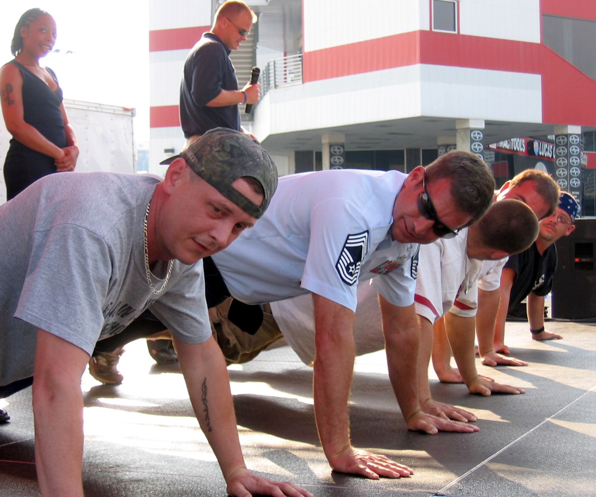 Staff Sgt. Travis Cambridge conducts a push-up competition at Bristol Motor Speedway’s Street Warriorz night in Tennessee June 2. Chief Master Sgt. Mark Anderson takes the lead in uniform. Both Airmen are members of the 332nd Recruiting Squadron. (U.S. Air Force photo)
