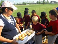 MINOT AIR FORCE BASE, N.D. -- Jamie Prock, wife of Master Sgt. James Prock, 91st Missile Maintenance Squadron, gives treats to her team, the ‘American Eagles’, after a well played game. Children, ages seven to nine, participated in a baseball game July 1 at “field one” in the summer youth baseball program at the David C. Jones Youth Center here. (U.S. Air Force Photo by Airman 1st Class Benjamin Stratton)
