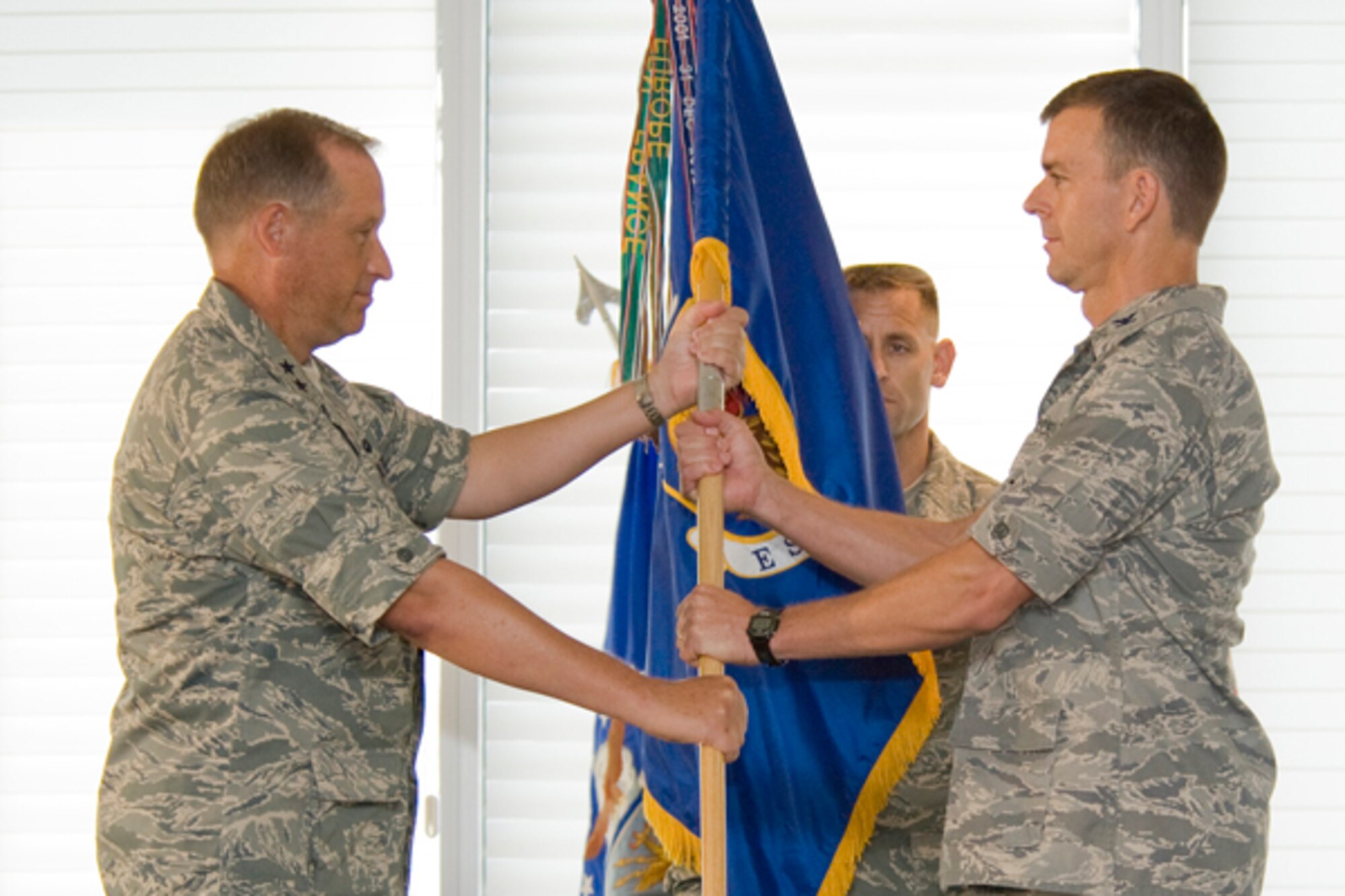Maj. Gen. David Eidsaune, program executive officer for weapons and commander, Air Armament Center, passes the flag to Col. Bruce McClintock, 96th Air Base Wing commander at the officers club July 2. (USAF photo by Deb Haussermann)