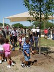 Members of Team Lackland take turns filling in the dirt for a new tree planted at the youth center in celebration of Arbor Day. Lackland's trees eliminate more than 80,000 tons of air pollution annually by removing air pollution created from industries and vehicles and producing clean oxygen. (USAF photo by Meredith Canales)         