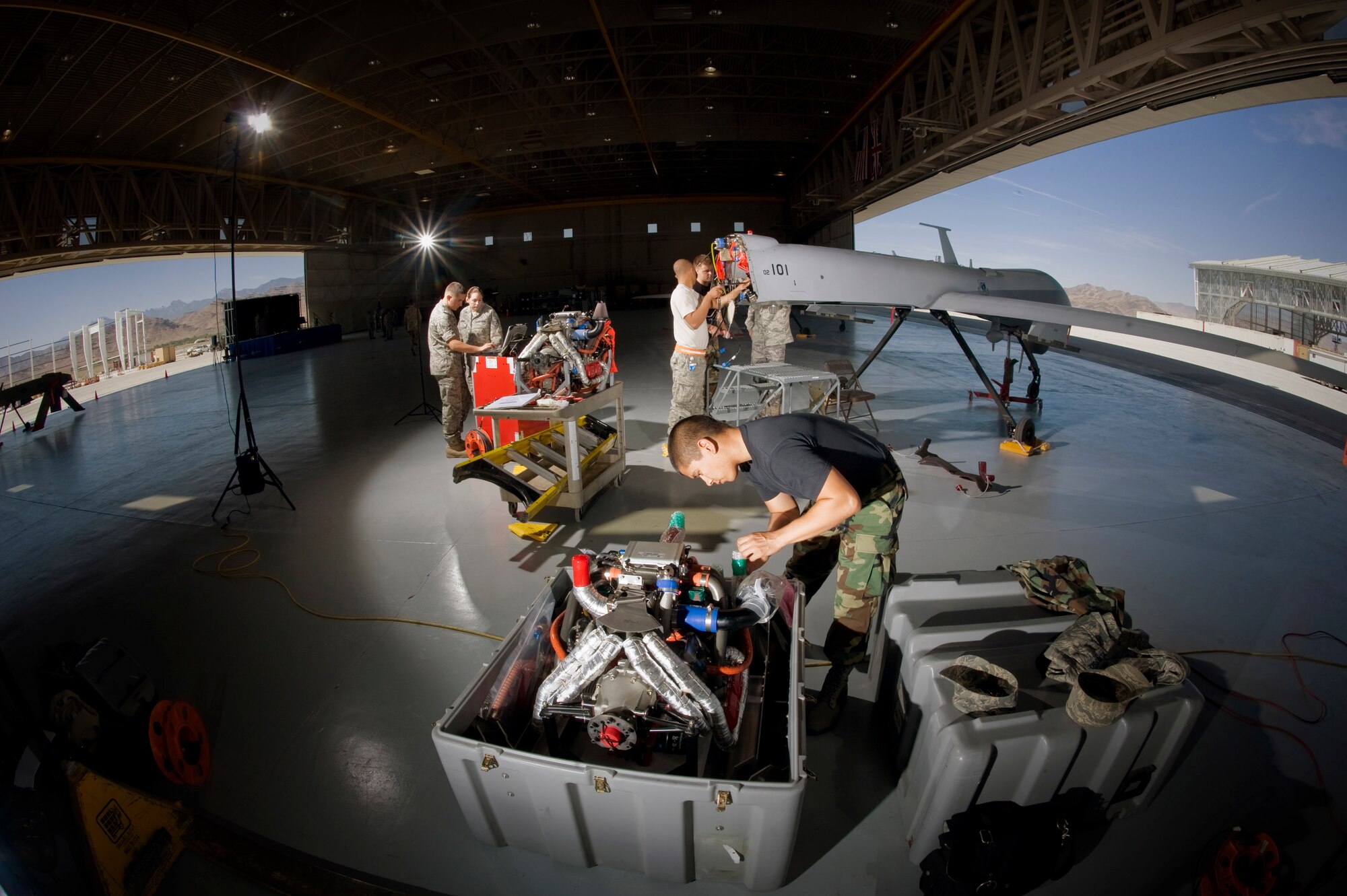Airmen from the 432nd Aircraft Maintenance Squadron work on one of the many unmanned aerial vehicles at Creech Air Force Base, Nev., June 19. Senior Airman Ignacio Reyes (right), ensures the Rotax engine for the MQ-1 Predator is sealed before boxing the engine for storage. Mr. Lester Sylvester shows Senior Airman Michael Osmun, how to the remove an oil line union, while Staff Sgt. Michael Rushing works on the union from inside the fuselage. Mr. Osmun is with Air Force Engineering and Technical Service. Staff Sgt. Alyssa Burns (second from left) shows structural maintenance technical data to Airman 1st Class Rex Leavitte. (U.S. Air Force photo/Lance Cheung)