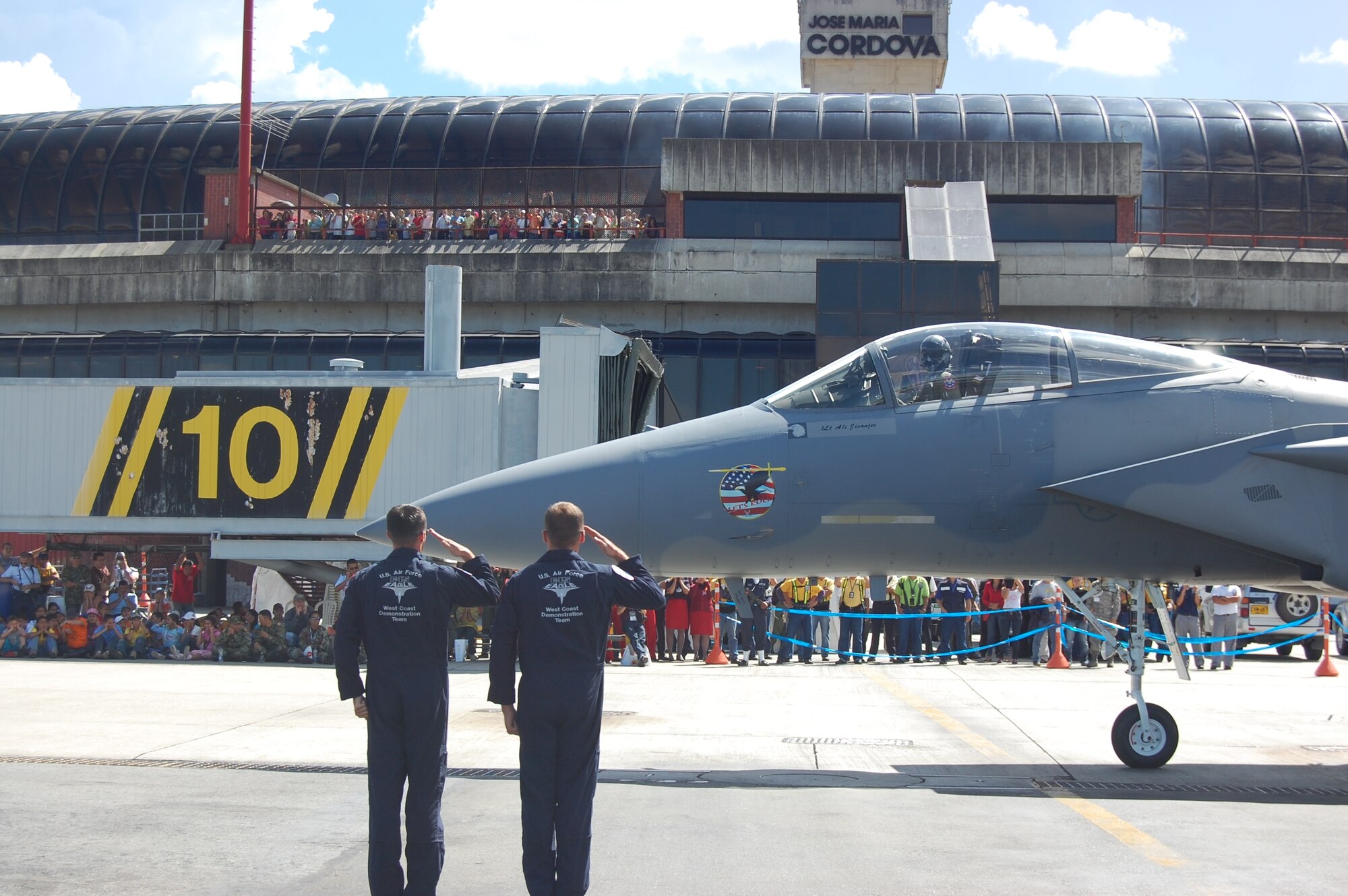 Members of the F-15 West Coast Demonstration Team salute the departing F-15C Eagle, flown by Capt. Sam Joplin, during the pre-flight portion of the team’s demonstration at the RIO NEGRO air and trade show venue in Medellín, Colombia. The Demonstration Team celebrated 25 years of service during RIO NEGRO by performing for audiences at the Medellín International Airport for six days, thrilling an audience estimated at more than 100,000 Colombian citizens. (Photo by Capt. Nathan Broshear) 