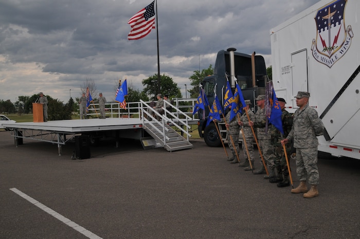 Five members of the 341st Missile Wing hold Malmstrom's new squadron flags in front of a payload transporter after the unveiling of the new 341st MW shield. Col. Michael Fortney, 341st MW commander, speaks during the re-designation ceremony at Medal of Honor Park July 1. (U.S. Air Force photo/John Turner)