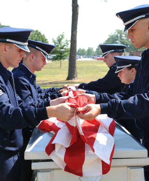SEYMOUR JOHNSON AIR FORCE BASE, N.C.- Base Honor Guard members Senior Airman Houston Kirkeide, Airman 1st Class Joseph Perry, Airman 1st Class Marcus Smith, Staff Sgt. Richard Allen, Senior Airman Tiffany Legree and Airman 1st Class Jason Hochsprung lift the flag from off the casket to fold June 24 here. The folding of the flag is honor and respect to the fallen servicemember. The flag is presented to the spouse, parents, child or other relative of the fallen servicemember. (U.S. Air Force photo by Airman 1st Class Whitney Stanfield) 