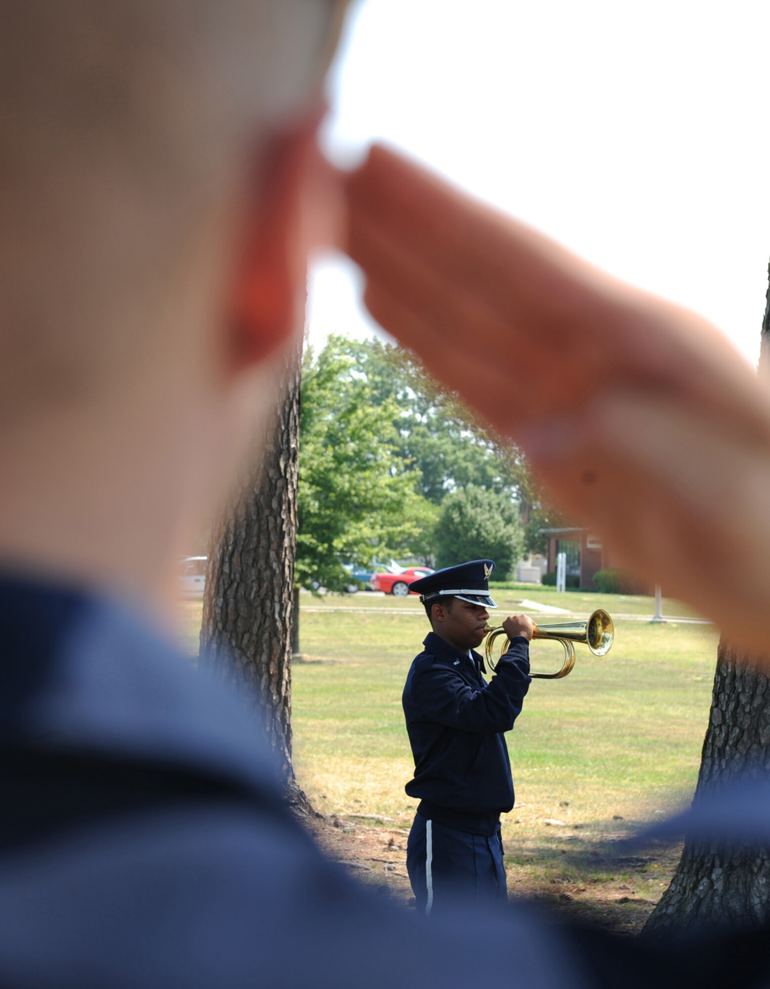 SEYMOUR JOHNSON AIR FORCE BASE, N.C.-Airman 1st Class Joseph Perry, base honor guard member, salutes while Airman 1st Class Marcus Smith plays "Taps" during a funeral drill practice on June 24. The Airmen practice every day to ensure their performance is at its peak.(U.S. Air Force photo by Airman 1st Class Whitney Stanfield)