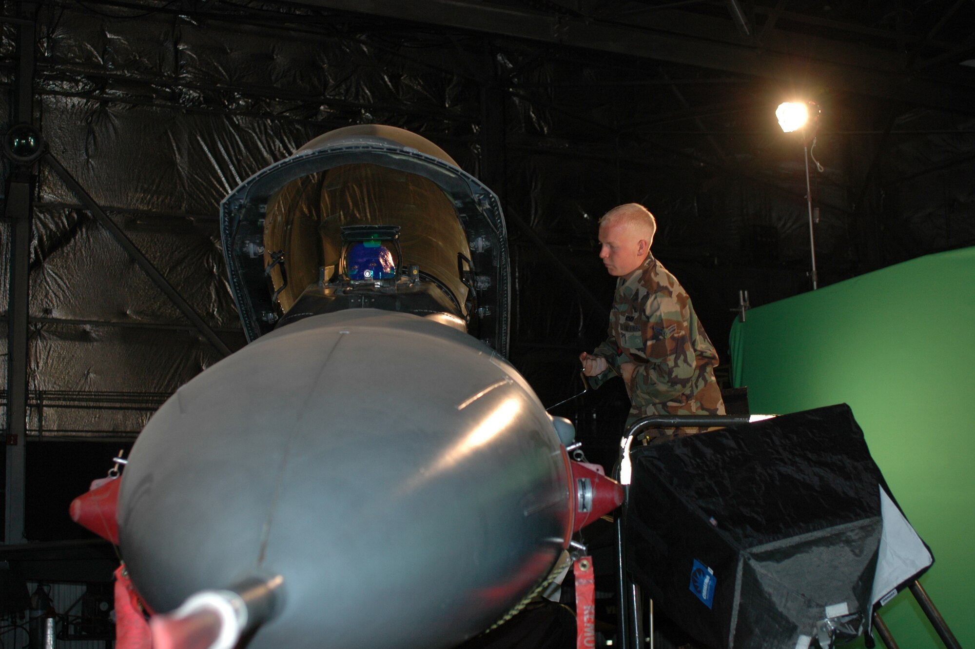 Airman 1st Class Jeff Swarthout, 4th Aircraft Maintenance Unit assistant dedicated crew chief, lowers the canopy of an F-16 during filming with the Blue Man Group July 2. The Las Vegas entertainment act visited Hill AFB to shoot a welcome video for Provo, Utah's Stadium of Fire Fourth of July celebration. The 388th Fighter Wing will perform a four-ship flyover at the event to mark the patriotic holiday and thank community members for their support of the Air Force mission. (Photo by 1st Lt. Beth Woodward)