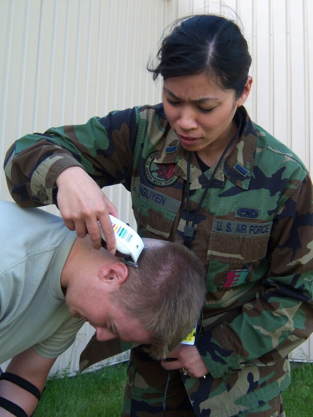 1st Lt. MarryAnne Nguyen, 28th Munitions Squadron material flight commander shaves the head of Airman 1st Class Aaron Voigt, 28 MUNS munitions storage crewmember June 27. A group of 14 shaved their heads as a symbolic gesture of support for Airman Voigt's mother who was diagnosed with breast cancer. (Courtesy photo/28 MUNS)