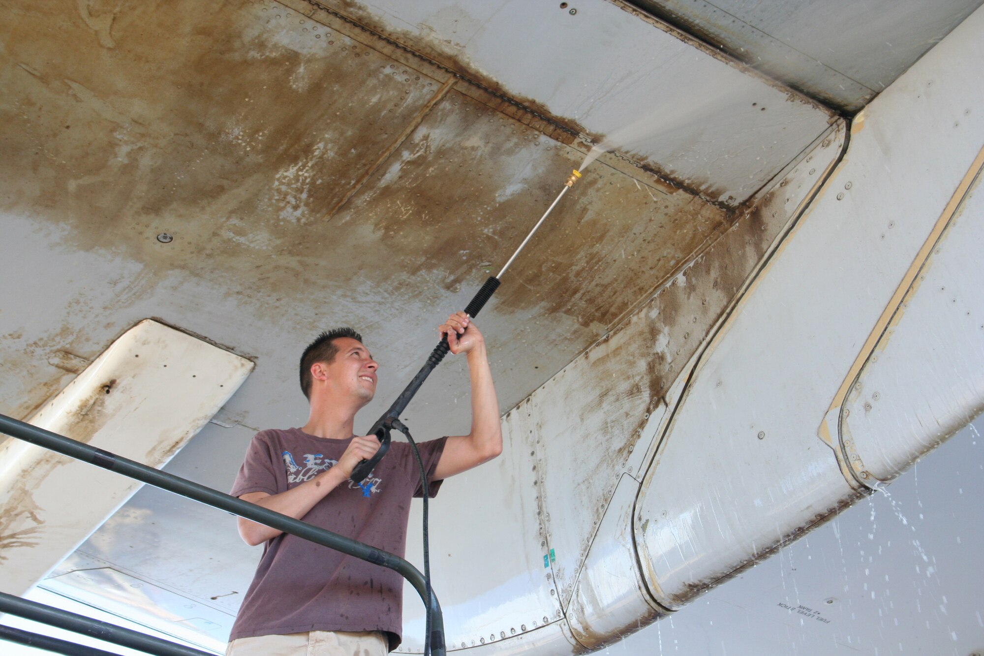 Tech Sgt. James Holzer, 412th Test Wing knowledge operations team chief, uses a hose to clean the bottom of a YC-15 wing here June 28. Volunteers from the base spent more than 200 hours preparing the aircraft for its dedication ceremony July 8. (Air Force photo by Chief Master Sgt. Luis Drummond)
