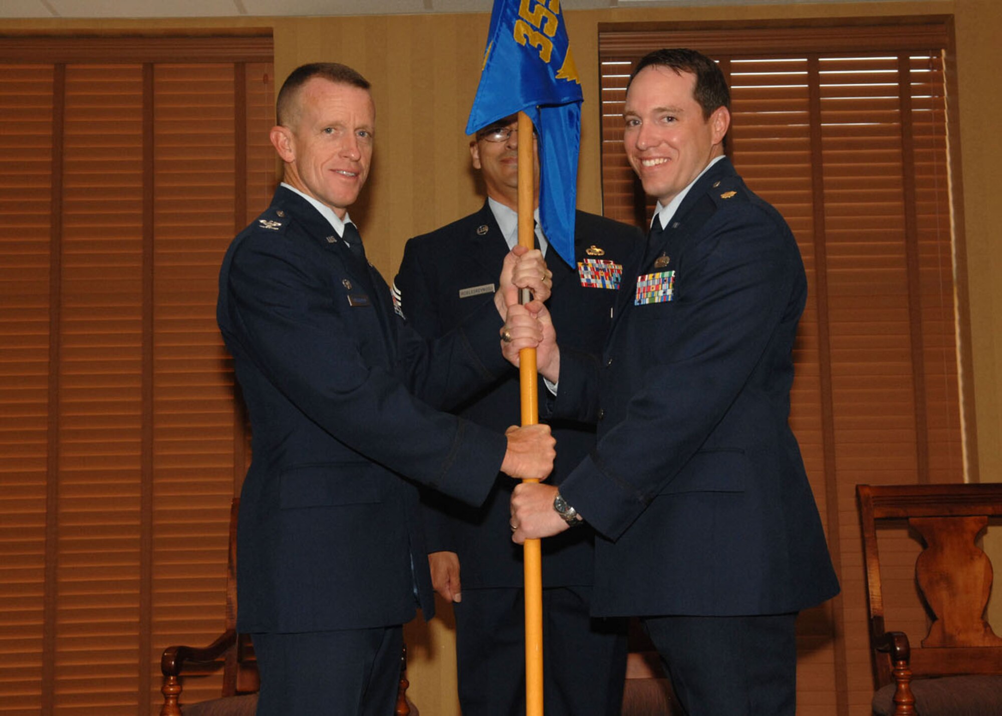 Maj. Douglas Pierce receives the 355th Comptroller Squadron guidon from Col. Kent Laughbaum, 355 Fighter Wing commander, during a change-of-command ceremony at the Officers’ Club July 3. Major Pierce took over command from Lt. Col. Catherine McLoud after serving as the commander of the 97th Comptroller Squadron, Altus Air Force Base, Okla.  (U.S. Air Force photo by Senior Airman Alesia Goosic)