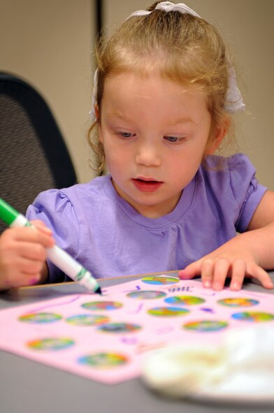 Three-year-old Carys White makes a picture to put into a care package for her deployed father Capt. Thomas White, 37th Expeditionary Bomb Squadron weapons system operator, on July 1. With help from the Airman and Family Readiness Center, friends and family members filled care packages with gifts and useful and special items for deployed Airmen. (U.S. Air Force photo/Senior Airman Marc I. Lane)