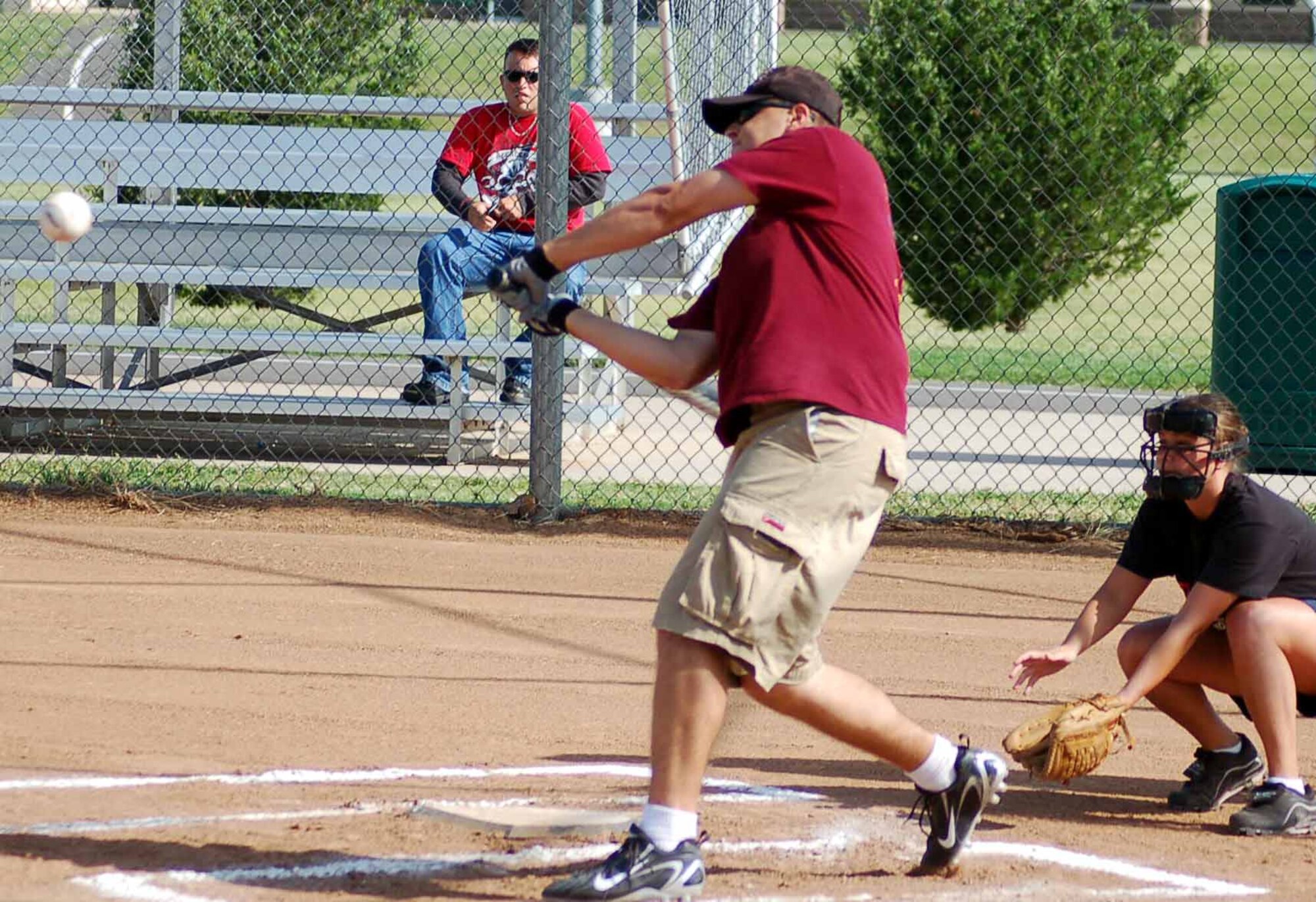 Terry Hutton, 31st Combat Communications Squadron third baseman, swings for the fences during the first inning of a June 25 game against the 552nd Operations Support Squdron as catcher April Rupprecht watches.  The 31st CCS won 24-21.  (Air Force photo by John E. Banks)