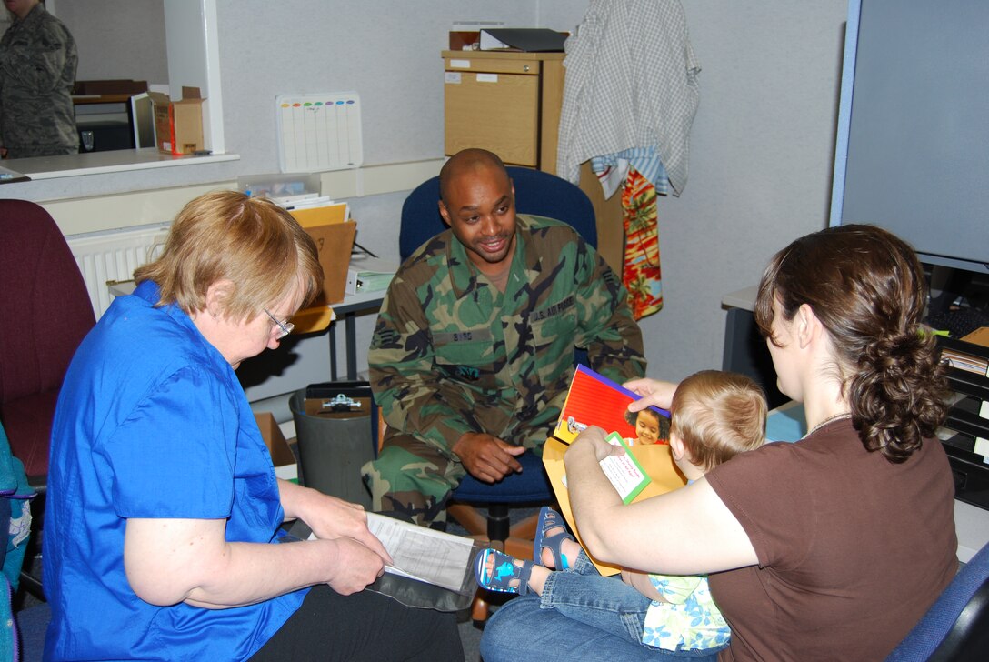 Senior Airman Robert Byrd from the 175th Mission Support Flight, Maryland Air National Guard on duty in RAF Mildenhall England looks on as a passport application is being processed for a newly assigned arrival with Mrs. Barbara from MPF. 
(U.S. Air Force Photo by Master Sgt. Edward Bard)