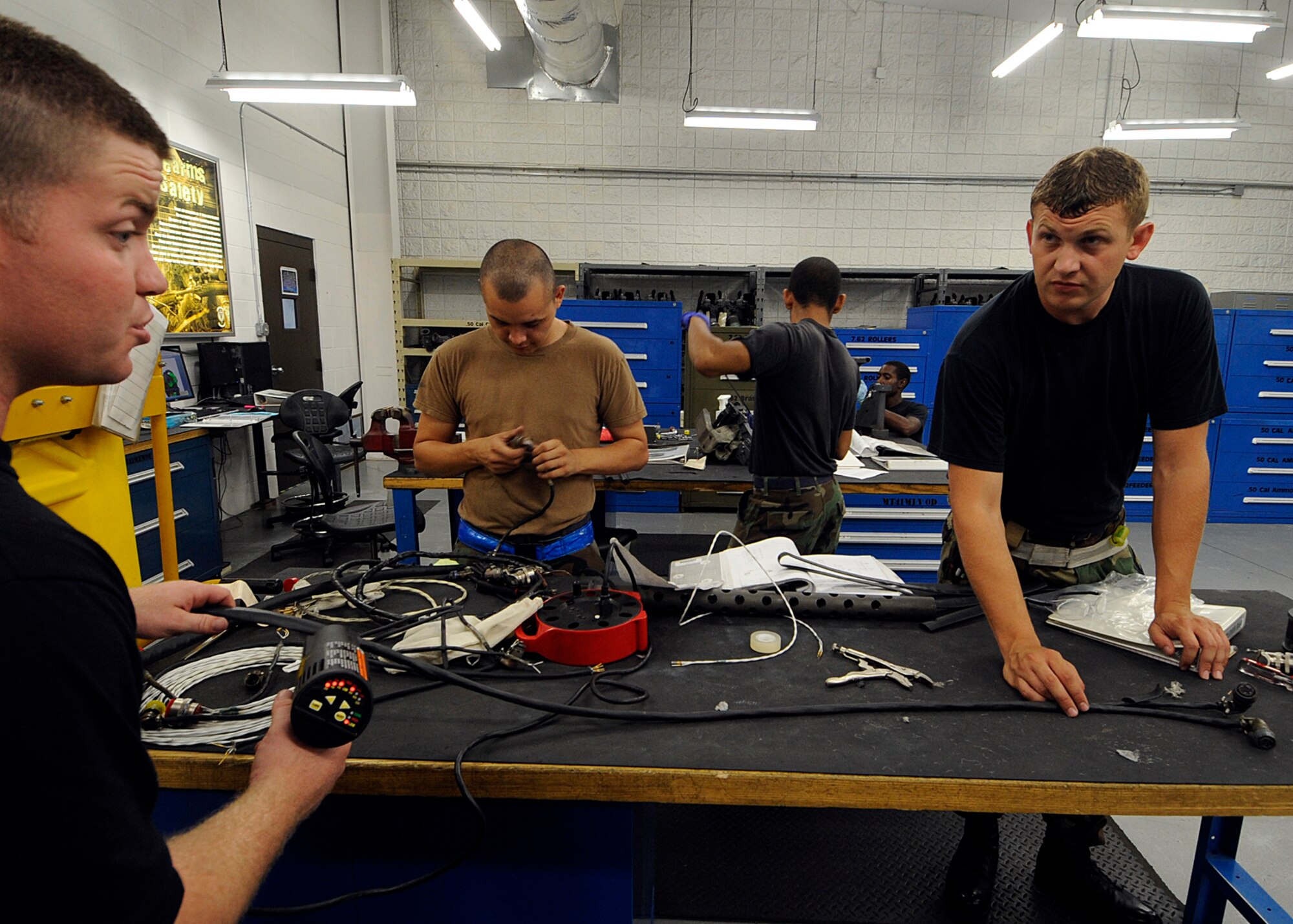 MOODY AIR FORCE BASE, Ga. -- Staff Sgt. Jason Fifield, 723rd Aircraft Maintenance Squadron armament flight technician, gives instruction to Airman 1st Class Ben Hardy, 723rd AMXS armament apprentice, as he shrinks a new cable with a heat gun. The cable was built from scratch in-house to replace an old unit. (U.S. Air Force photo by Airman 1st Class Brittany Barker)