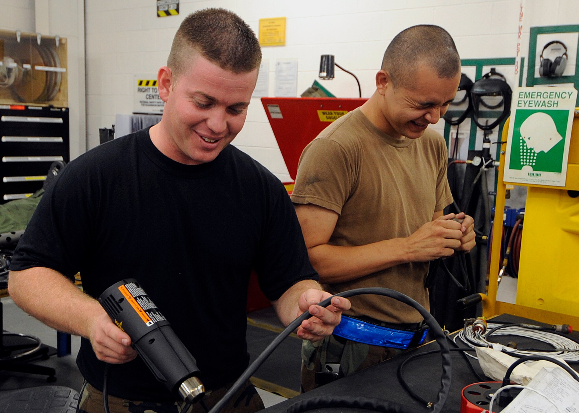 MOODY AIR FORCE BASE, Ga. -- Airman 1st Class Ben Hardy and Airman 1st Class Dustin Reese, 723rd Aircraft Maintenance Squadron armament flight technicians, shrink a weapons control cable with a heat gun. The cable supplies power to a gun station on an HH-60G Pave Hawk. (U.S. Air Force photo by Airman 1st Class Brittany Barker)