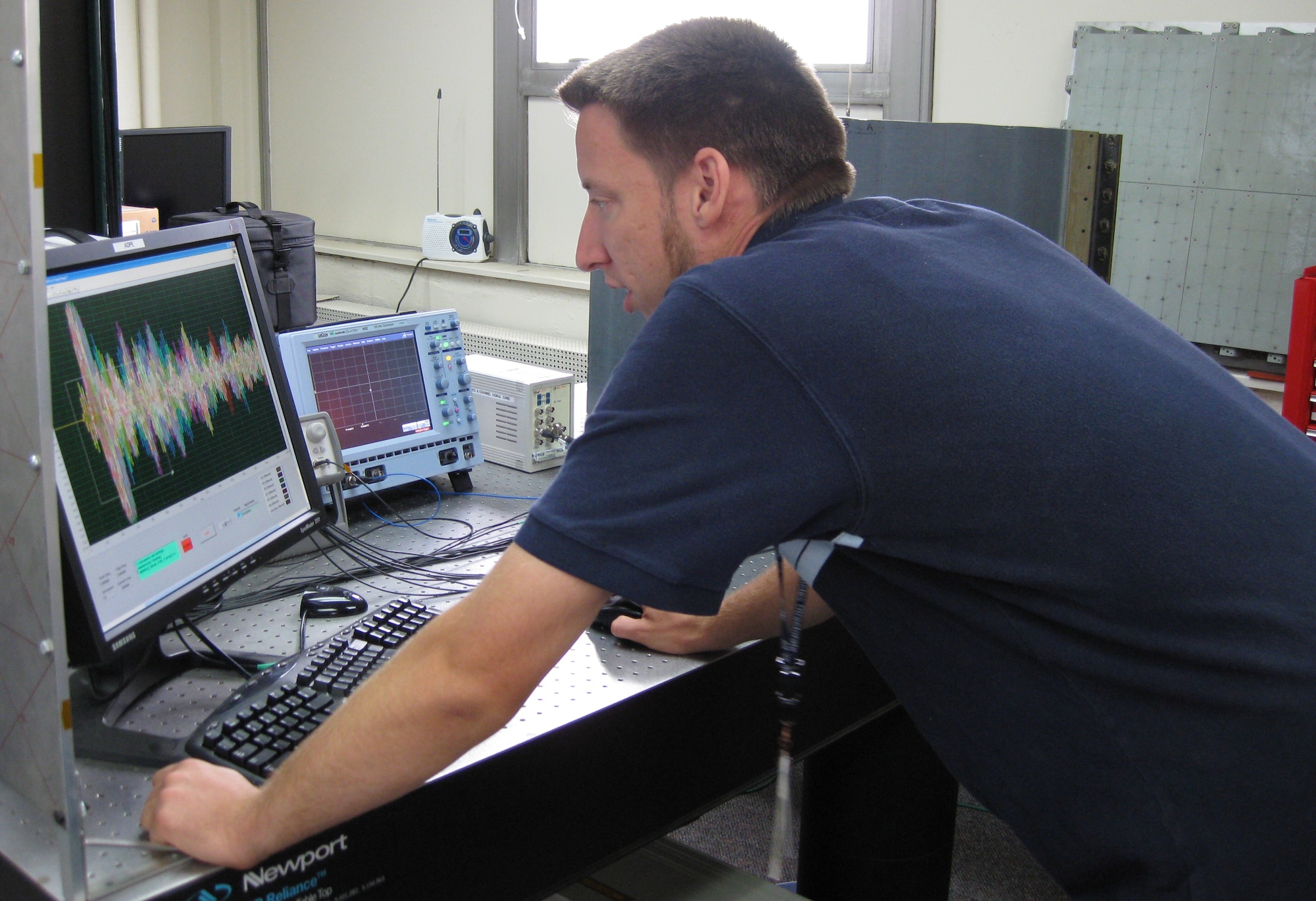Kevin Brown, an Air Force Research Laboratory engineer at Wright-Patterson Air Force Base, analyzes signals from a piezoelectric sensor array attached to a Global Hawk test article that has been subjected to impact loads.  The sensor array, which can be used to detect structural damage, is one component of the Integrated Systems Health Management system.  (U.S. Air Force photo)