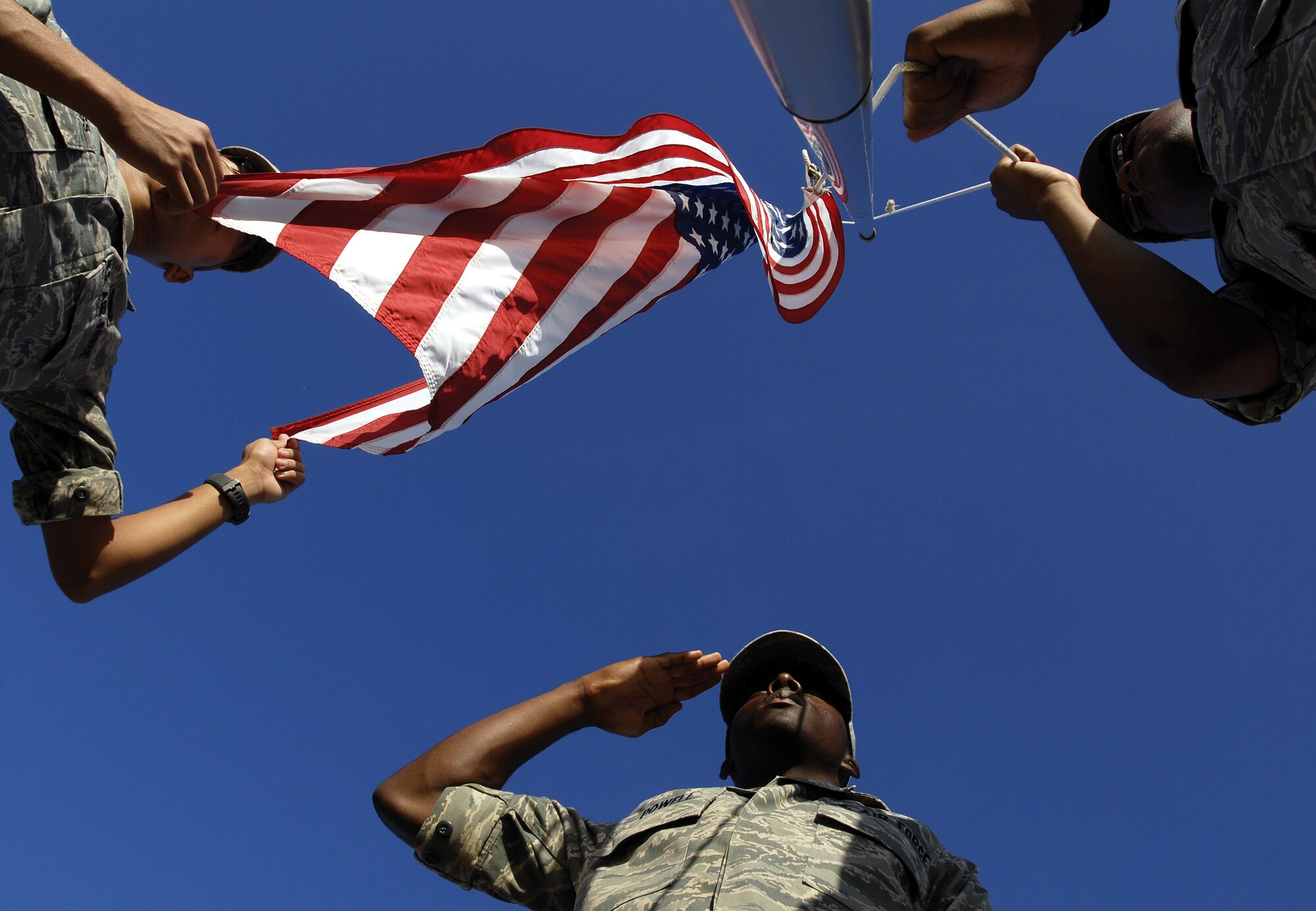 Airman Bryant Thompson and Airman First Class Kevin Stallings raise the Colors at the Goodfellow Air Force Base parade grounds as Airman Jesse Powell renders a salute. Airmen Thompson and Stallings are members of the 316th Training Squadron. Airman Powell is a member of the 315th Training Squadron. (U.S. Air Force photo by Master Sgt. Randy Mallard)