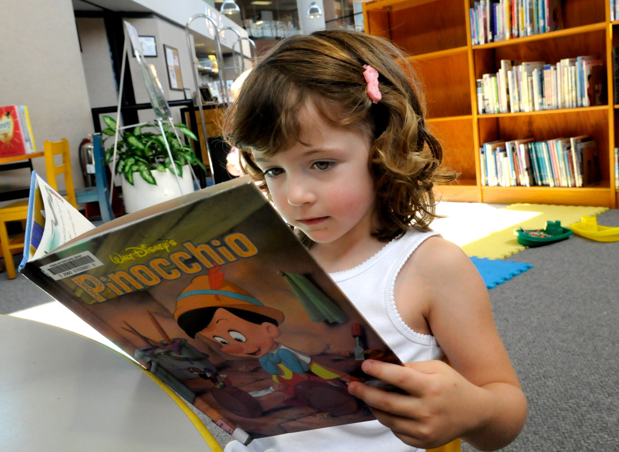 Alexa Smith,4, finds a good book to read in the library June 17. U. S. Air Force photo by Sue Sapp