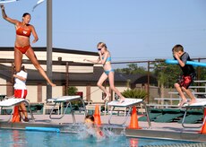 Allison Clayton and several children jump in to the deep end at the base swimming pool June 27. Mrs. Clayton is a lifeguard at the swimming pool on base. Swimming lessons are available at the base swimming pool for infants through adults; call the Outdoor Recreation Center at 963-1672. (U.S. Air Force photo/Airman 1st Class Timothy Taylor)