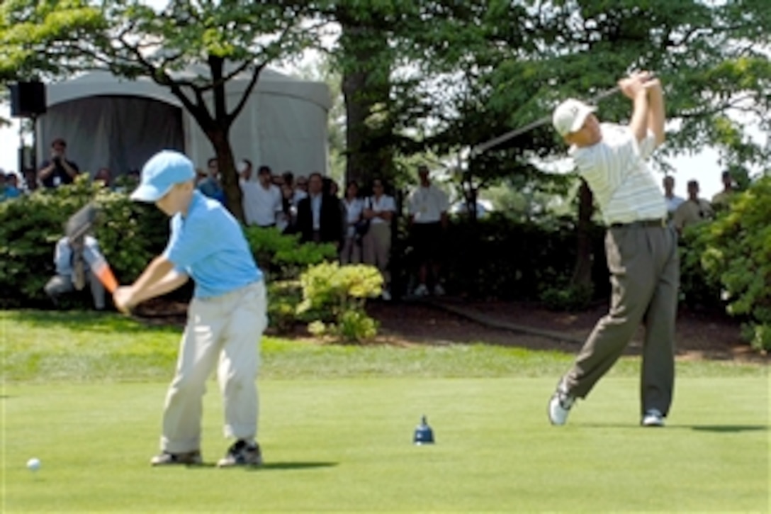 Jeffrey Dahl, 9, left, and professional golfer Fred Couples hit the ceremonial first shots to open the second AT&T National golf tournament, July 2, 2008, at Congressional Country Club in Bethesda, Md. Dahl, who is from New Jersey, hit the shot along with Margaret Rollins, 13, from Virginia. Both the children's fathers are servicemembers, and the two were part of a group of 20 military children honored during the tournament.