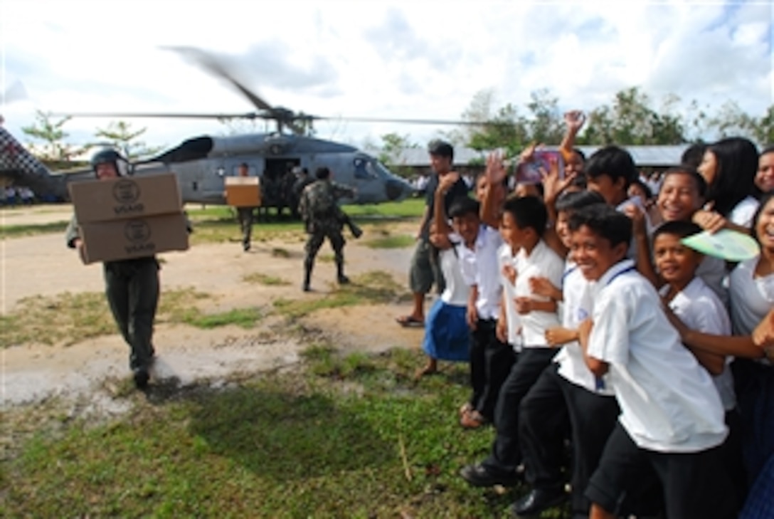 U.S. Navy Petty Officer 2nd Class Jeremy Thomas carries relief supplies to the citizens of the Municipality of Balasan on Panay Island, Philippines, on July 1, 2008.  Thomas is a helicopter crewman with Helicopter Anti-Submarine Squadron 4 and is flying missions to the island delivering food and water in the wake of Typhoon Fengshen.  At the request of the government of the Republic of the Philippines, the aircraft carrier USS Ronald Reagan (CVN 76) is off the coast of Panay Island providing humanitarian assistance and disaster relief.  The Ronald Reagan is operating in the 7th Fleet area of responsibility to support maritime security operations.  