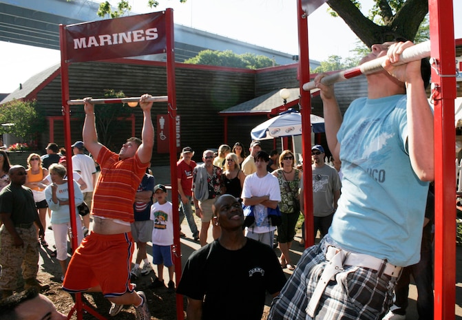 Mike Dickinson (left) and Mike Marx compete against each other to see who can do the most pull-ups July 5 at Summerfest. Marines challenged the music festival attendees to either perform a max set of pull-ups or a flexed-arm hang as long as possible to raise awareness of the Marine Corps.