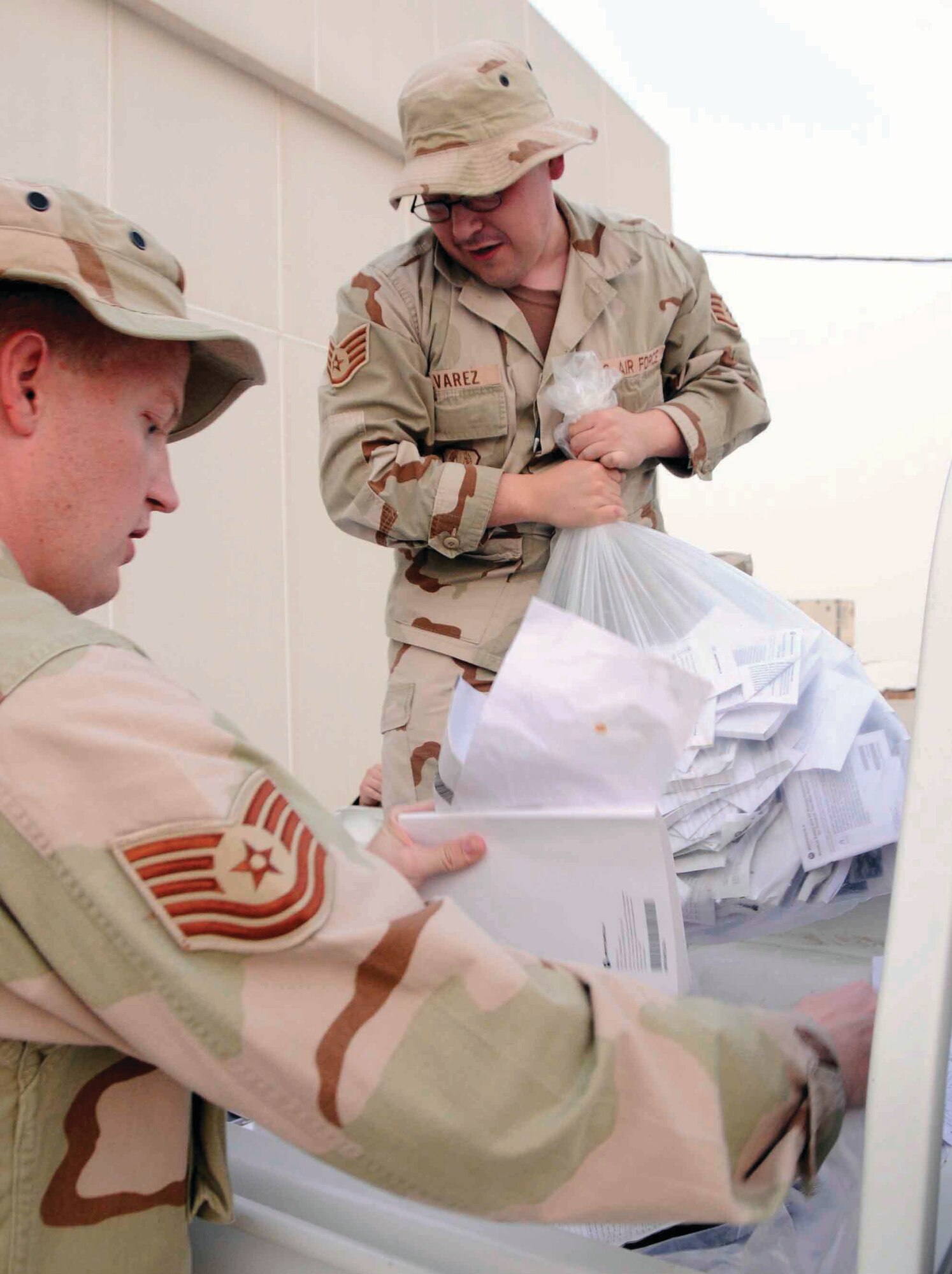 SOUTHWEST ASIA -- Technical Sgt. Christopher Hofman (front), and Staff Sgt. Michael Alvarez (back) and their 379th Expeditionary Communications Squadron coworkers unload a truck full of outdated manuals to eliminate the waste inside their office space July 2. (U.S. AIr Force photo/Senior Airman Domonique Simmons)