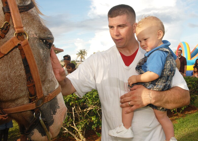 Joe Radosevich of the 36th Munitions Squadron, introduces 13 month old son Hadyn to horses during Freedom Fest at Arc Light Park here July 3. Freedom Fest is hosted by the 36th Force Support Squadron and held annually to recognize and celebrate our Independence Day. (U.S. Air Force photo by Airman 1st Class Nichelle Griffiths)
