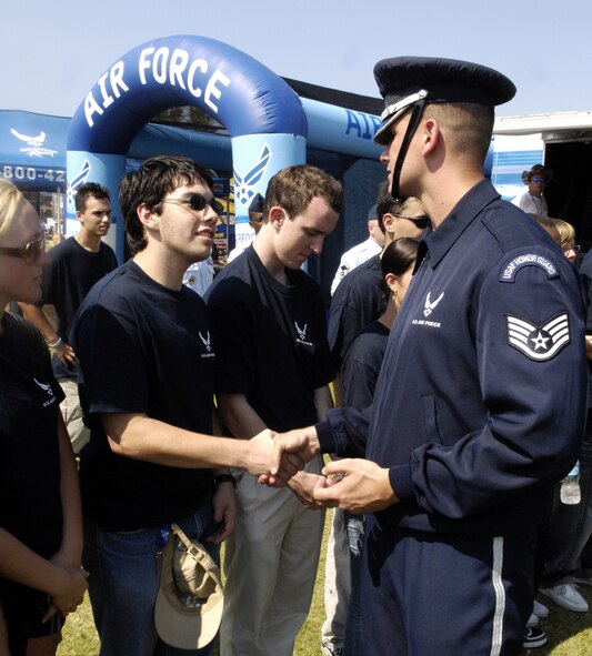 Staff Sgt. Michael Doss, U.S. Air Force Honor Guard Drill Team, hands drill team coins to new Air Force inductees July 4 at the Daytona International Speedway in Daytona Beach, Fla. The drill team is the traveling component of the Honor Guard and tours worldwide representing all Airmen while showcasing Air Force precision. (U.S. Air Force photo by Airman 1st Class Sean Adams)