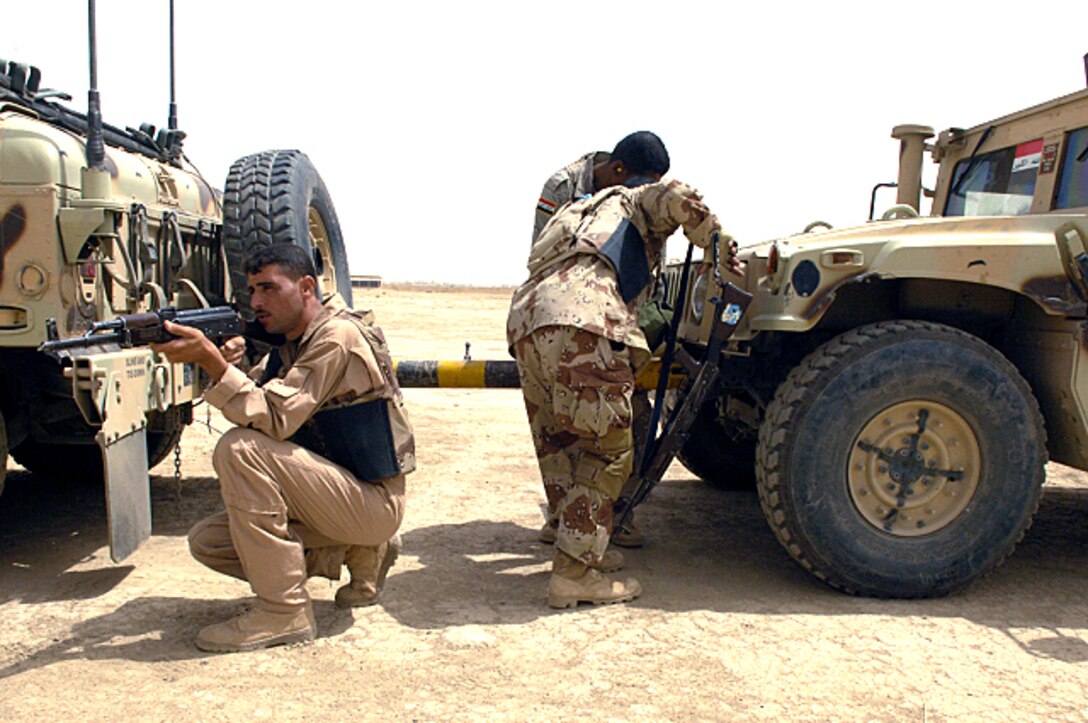 An Iraqi soldier covers for his teammates while they connect a tow bar to a disabled HUMVEE during an exercise to train soldiers on how to react to improvised explosive devices, or bombs, on Camp Echo, Iraq, July 2, 2008. 