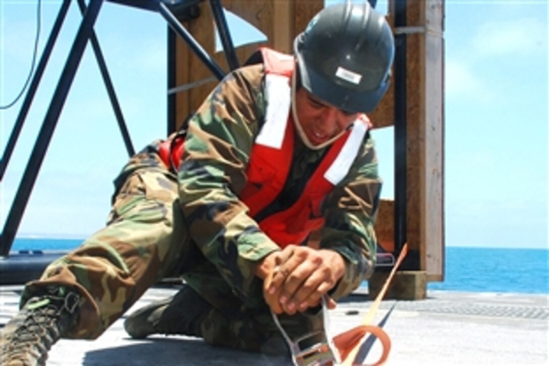 U.S. Navy Seaman Rafael Garcia secures a structural piece of the Navy Elevated Causeway System off-loaded from the Military Sealift Command auxillary crane ship SS Flickertail State onto the Improved Navy Lighterage System Causeway Ferry 1 during Joint Logistics Over-The-Shore 2008, Del Mar, Calif., June 30, 2008. Garcia is assigned to Amphibious Construction Battalion 1.