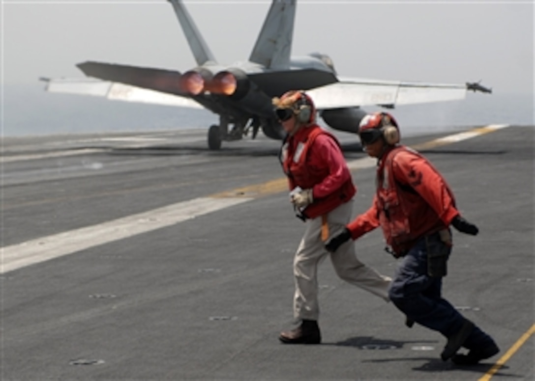 U.S. Navy Lt. Ross Drenning, of Carrier Air Wing 2, and an aviation ordnanceman run to the next cycle during flight operations aboard the Nimitz-class aircraft carrier USS Abraham Lincoln (CVN 72) as an F/A-18E Super Hornet launches in the background while underway in the Persian Gulf on June 30, 2008.  The Lincoln is deployed to the U.S. 5th Fleet area of responsibility to support maritime security operations.  