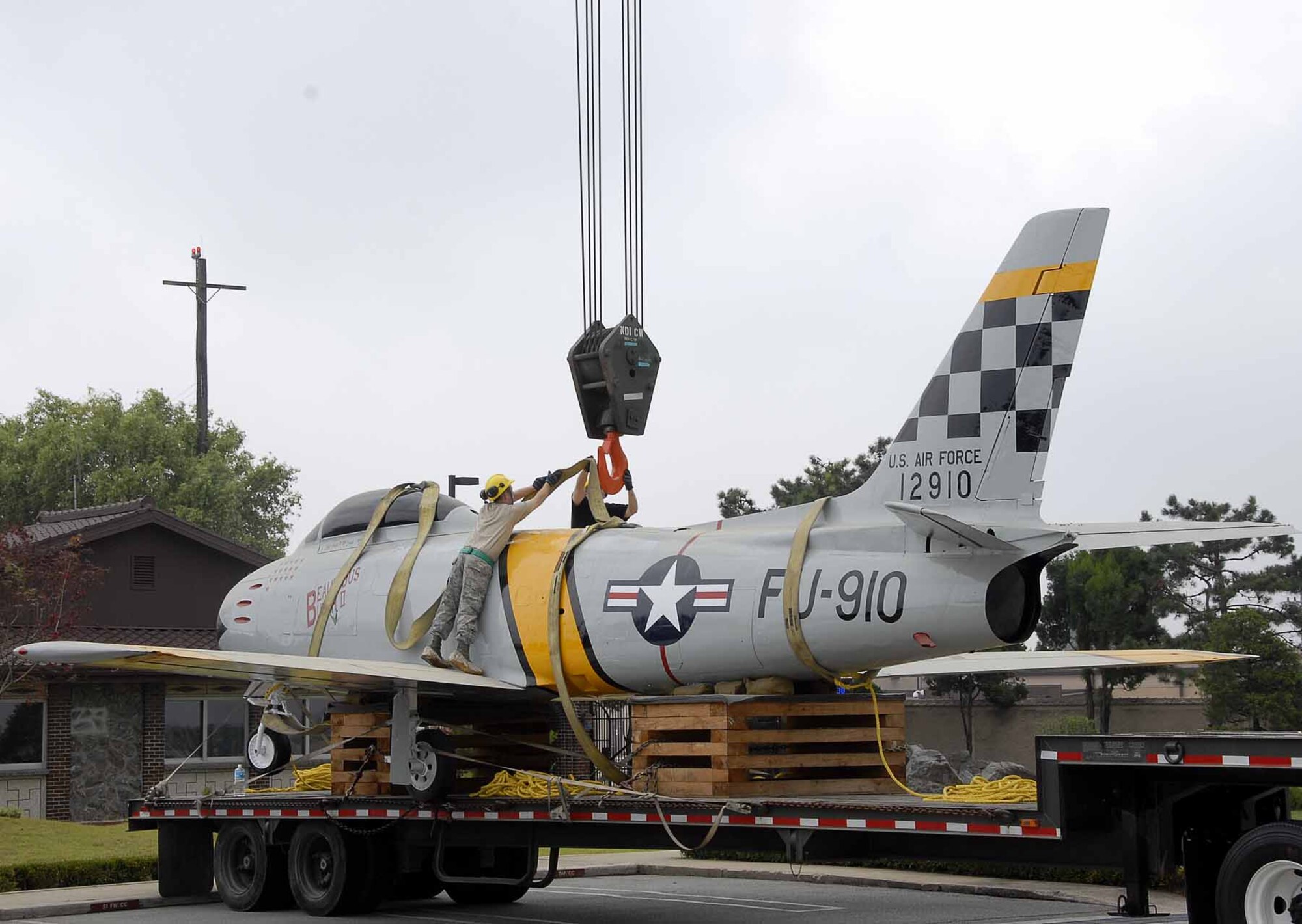 OSAN AIR BASE, Republic of Korea -- Members of the 51st Maintenance Squadron  attach a crane to a F-86 Sabre aircraft static display  in preparation to move the aircraft to its final resting place in front of base operations here July 3. The placement was the final portion of a restoration project than entailed more than 100 man-hours which included removing years of weathered paint, coatings and distinctive markings. In addition, technicians applied a weather-resistant polyurethane coating designed to protect the historic aircraft from the elements. (U.S. Air Force photo/Staff Sgt. Scottie McCord)