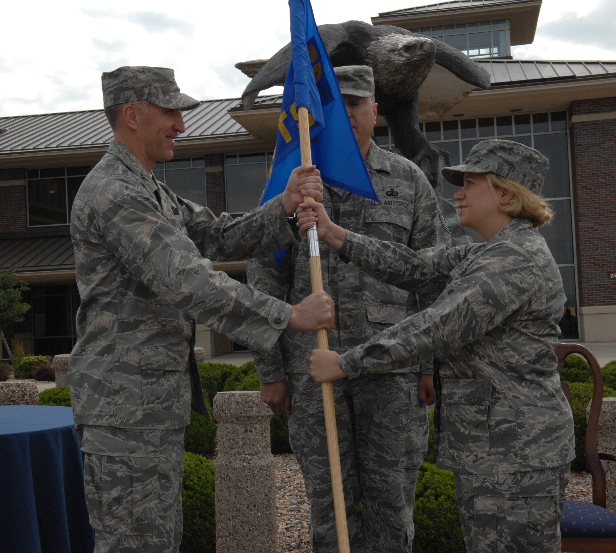 Col. Scott Vander Hamm, 28th Bomb Wing commander, passes the 28th Comptroller Squadron guidon to Lt. Col. Christine Wasdin, who assumed command of the 28 CMPTS July 8 at the Rushmore Center.  Colonel Wasdin served as the Operations and Maintenance Desk Officer Branch chief at the U.S. Special Operations Command J-8 Comptroller Directorate at MacDill Air Force Base, Fla. (U.S. Air Force photo/Airman 1st Class Adam Grant)
