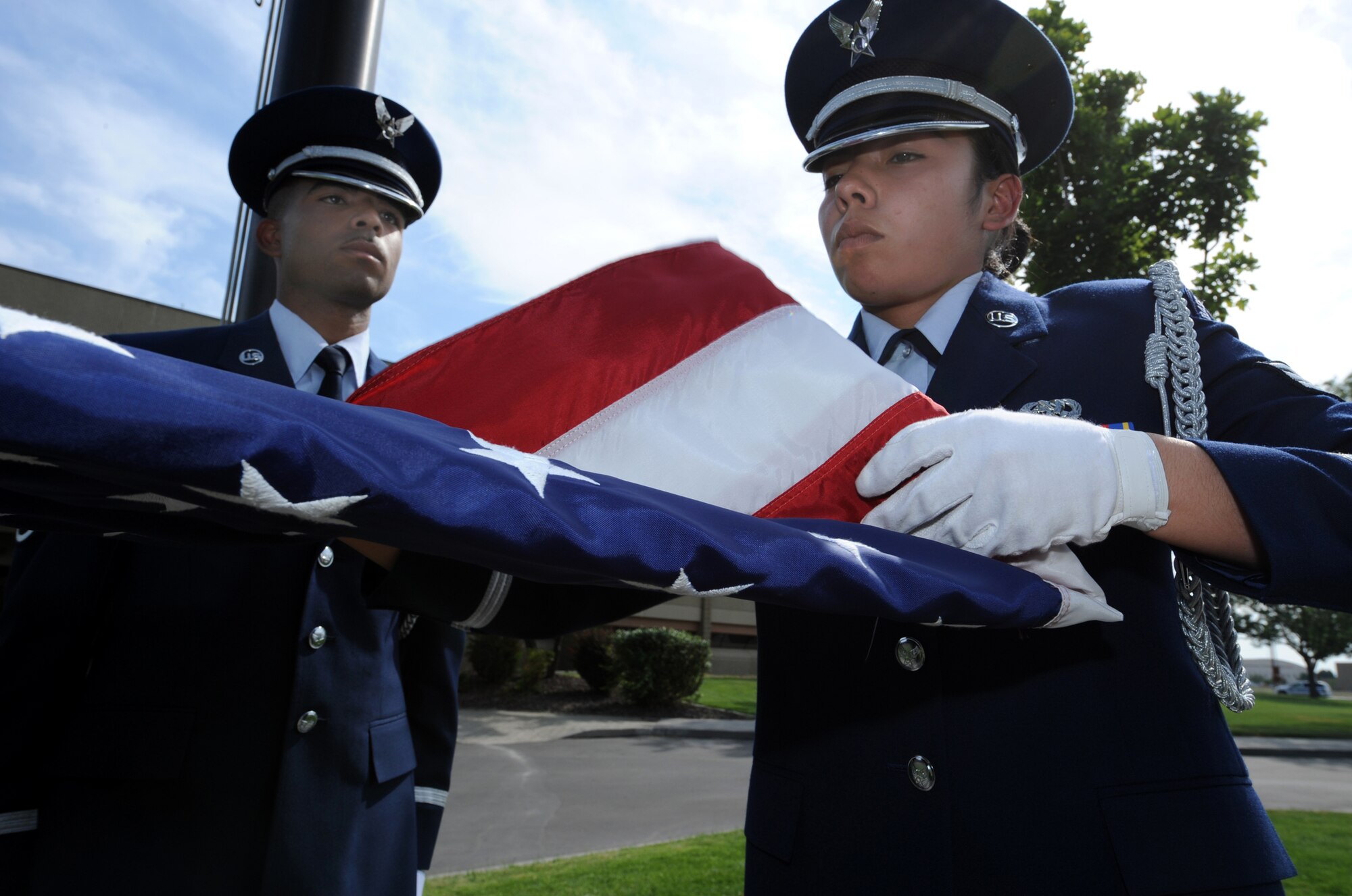 MOUNTAIN HOME AIR FORCE BASE, Idaho - Staff Sgt Emmanuel Santillan, (left) 366th Services Squadron honor guard member, helps fold the American flag with fellow honor guard member Senior Airman Cindy DeLeon, 366th Component Maintenance Squadron honor guard member, at the 366th Fighter Wing formal retreat July 1. The base honor guard performs many functions around the base to support the wing. (U.S. Air Force photo/ Airman 1st Class Stephany Miller)