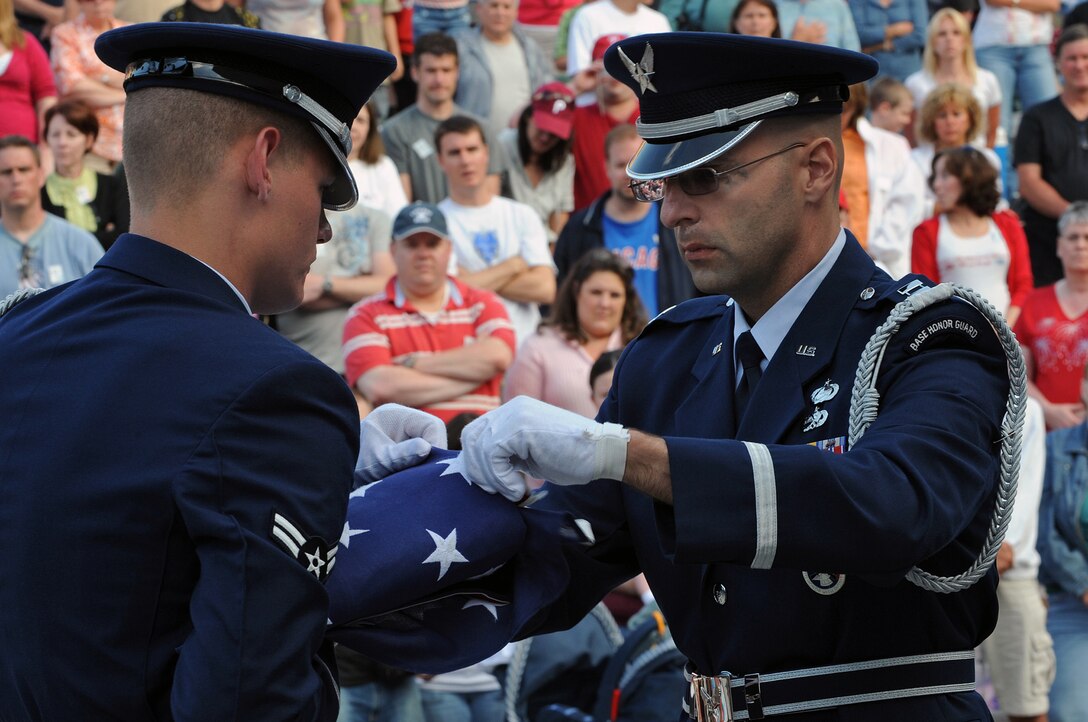 (Left) Airman 1st Class Daniel McMillan and Capt. Paul Hubenthal, Headquarters Air Reserve Personnel Center Honor Guard members from Buckley Air Force Base, Colo., fold the American flag during a flag presentation ceremony at Mount Rushmore National Memorial, July 3. Approximately 30,000 people came to the memorial for the 2008 Independence Day Celebration. (U.S. Air Force photo/Senior Airman Marc I. Lane)