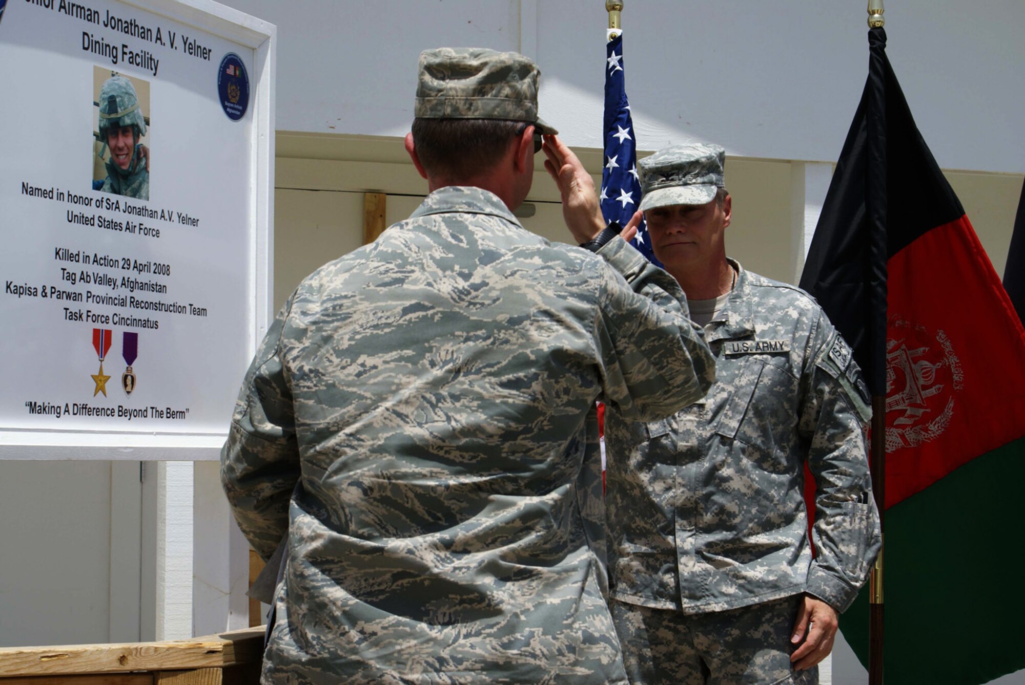 Air Force Lt. Col. William D. Andersen, Kapisa-Parwan Provincial Reconstruction Team commander, salutes U.S. Army Col. Jonathan Ives upon uncovering the sign dedicating a Dining Facility on Bagram Air Field to Senior Airman Jonathan A.V. Yelner.  Yelner was killed when an improvised explosive device detonated underneath his vehicle April 29 in Tag Ab Valley, Kapisa province, Afghanistan. (U.S. Army photo/Army Capt. Elizabeth Casebeer)