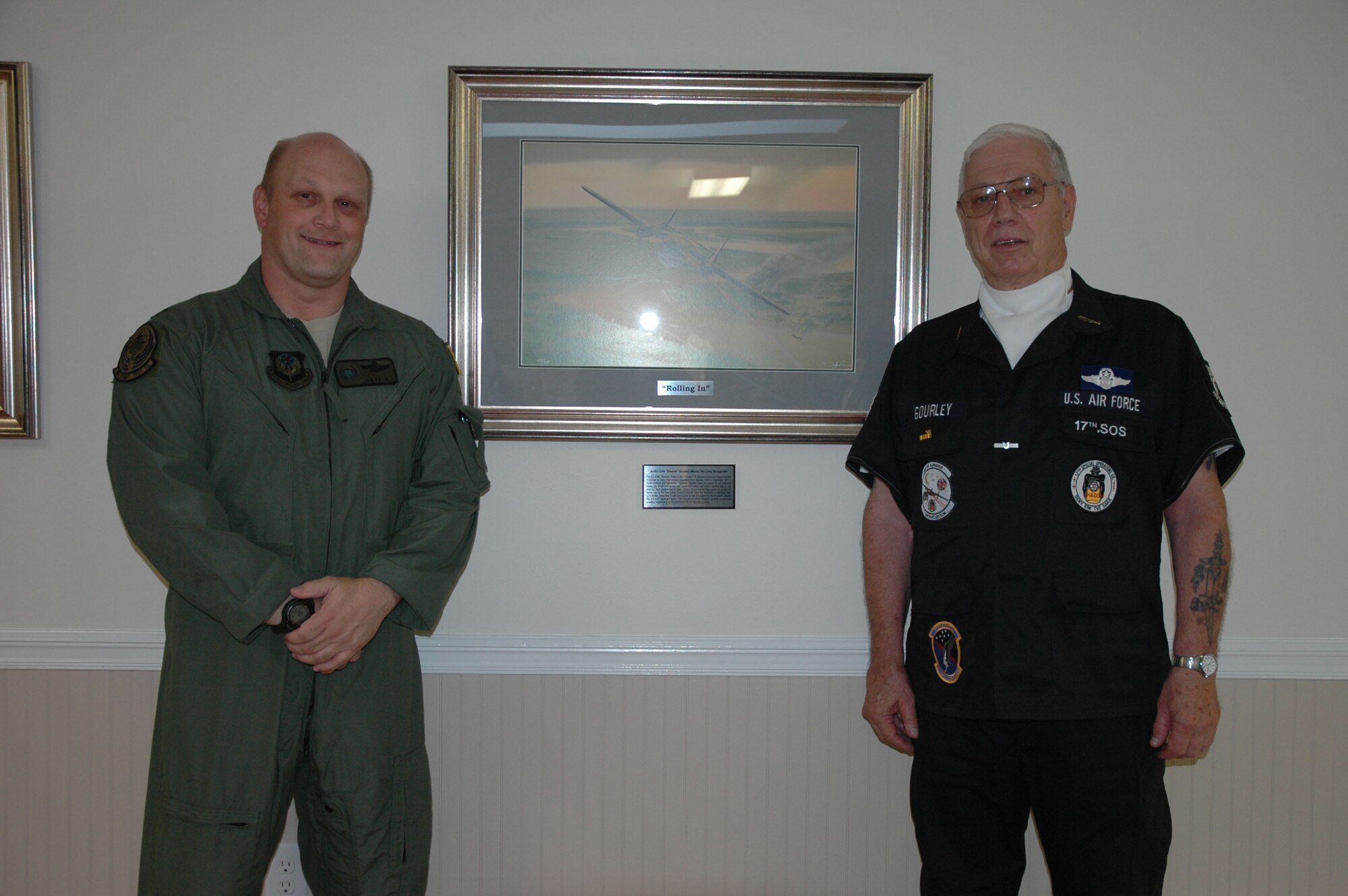 Lt. Col. Donald Peck, 18th Flight Test Squadron commander, and Garrettson "Garry" Gourley, retired U.S. Air Force flight engineer, flank a lithograph donated to Teresa Village during a ceremony there on July 8. The original painting, by Darby Perrin, titled "Rolling In," depicts an AC-119G Shadow attacking a Viet Cong stronghold during the Viet Nam War. Gourley, a resident of Teresa Village, one of three Air Force Enlisted Village sites, was a member of the 17th Special Operations Squadron, which flew the AC-119G. The 18th FLTS has a direct lineage to the 17th SOS, and Colonel Peck took a special interest in the AC-119 gunship and its history. (U.S. Air Photo by Master Sgt. Buffy Galbraith)