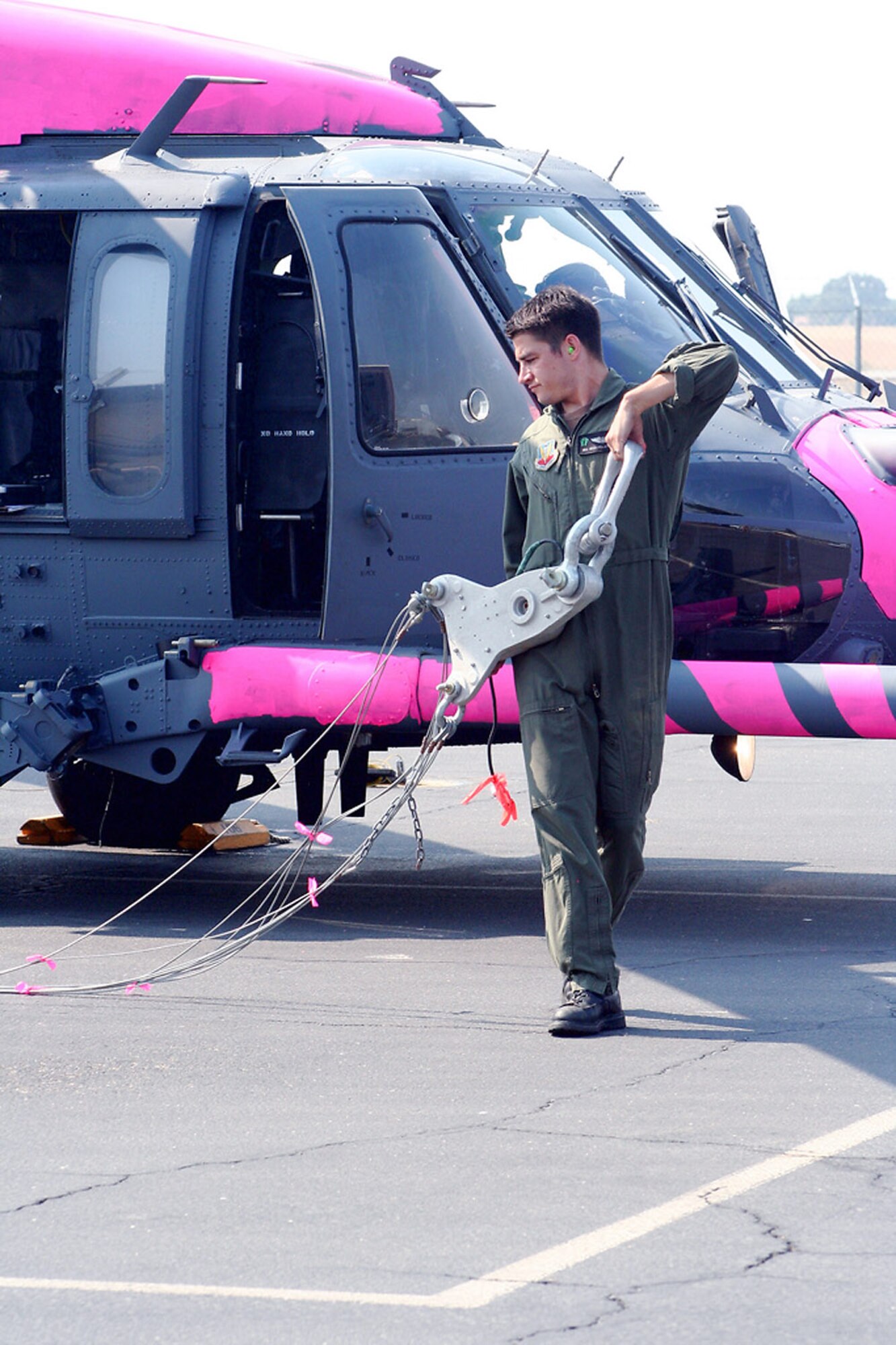 Senior Airman Sean Pellaton pulls a water bucket hoist July 2 near Sacramento, Calif. Aircrews trained with water buckets to become certified for firefighting suppression duty. Airman Pellaton is an HH-60G flight engineer from the 129th Rescue Wing of the California Air National Guard. (U.S. Air Force photo/Master Sgt. Barbara Apkarian) 
