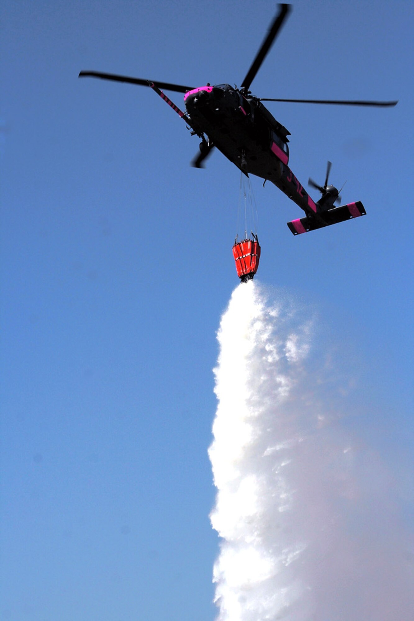 An HH-60G Pave Hawk releases water from an attached bucket July 2 near Sacramento, Calif. The aircrews trained with water buckets to become certified for firefighting suppression duty. The HH-60G is from the 129th Rescue Wing of the California Air National Guard. (U.S. Air Force photo/Master Sgt. Barbara Apkarian) 
